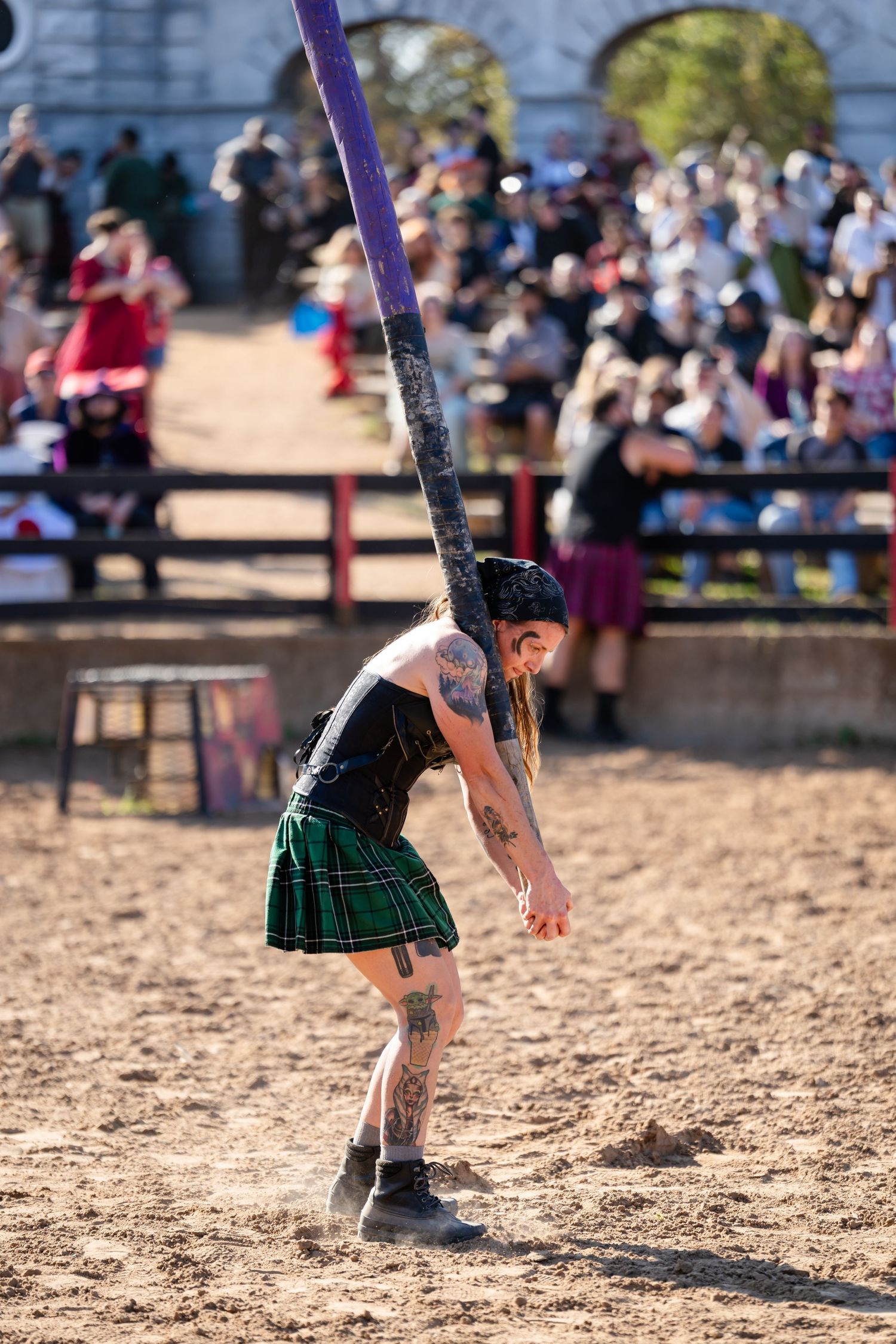 Close-up of legs wearing a green plaid kilt performing traditional Scottish highland dance moves in sand.
