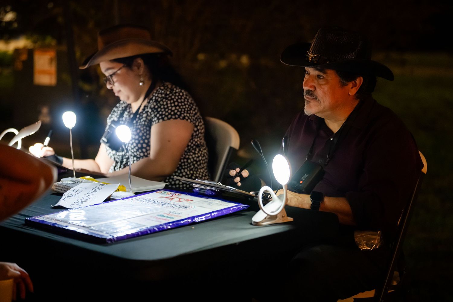 Artists work on illuminated light tables in a dark room creating detailed artwork at night.