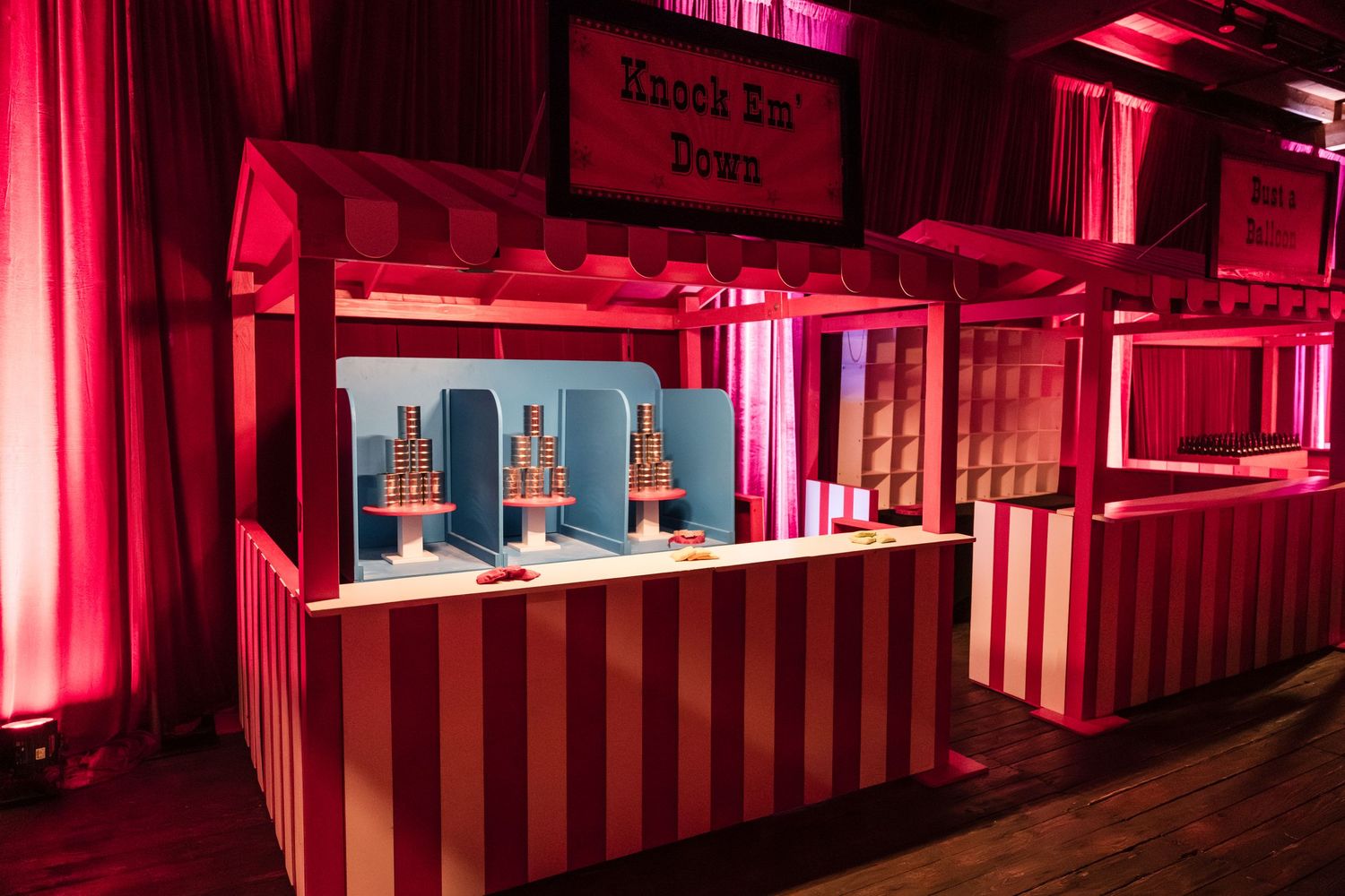Red-lit hallway with dramatic lighting and striped walls creates an immersive entertainment venue atmosphere.