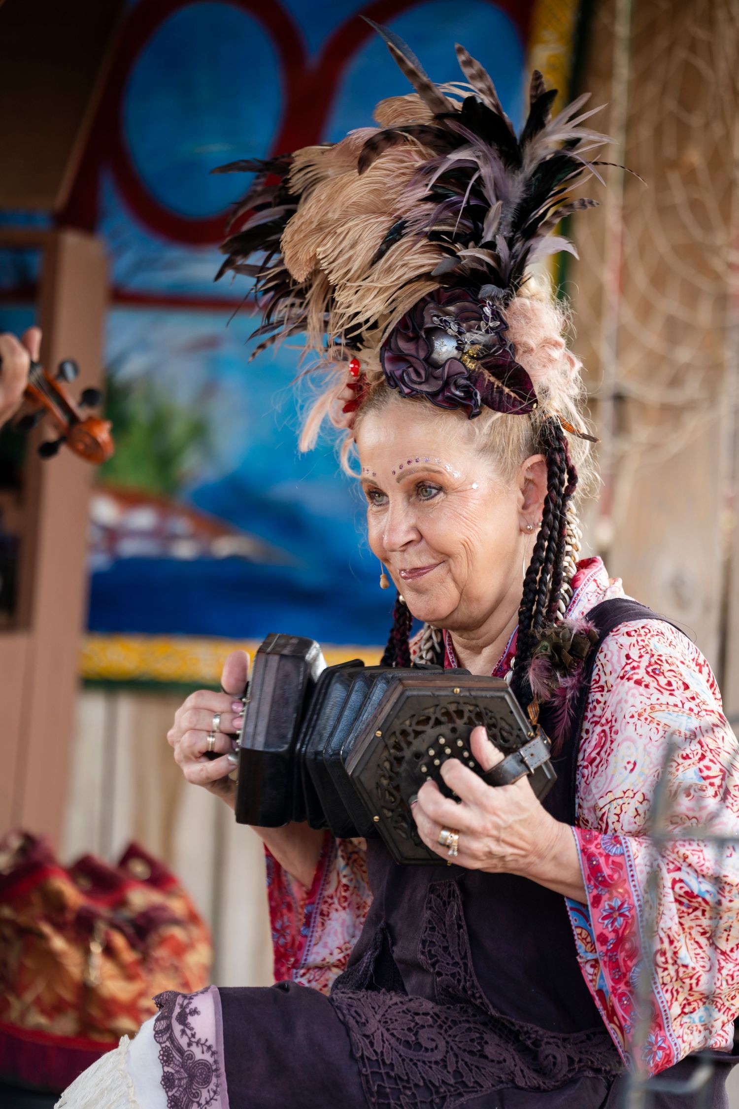 Person in vintage-style clothing and feathered headpiece sips from a teacup at a themed event.