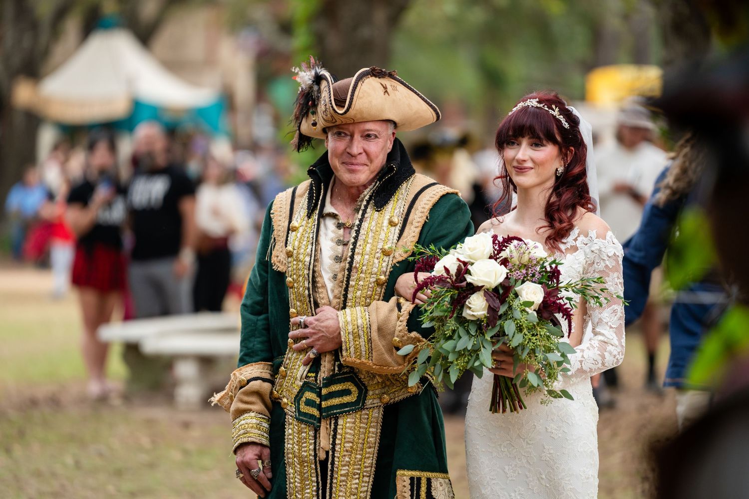 A couple in traditional Scottish wedding attire with tartan kilts and formal dress pose in a garden setting.