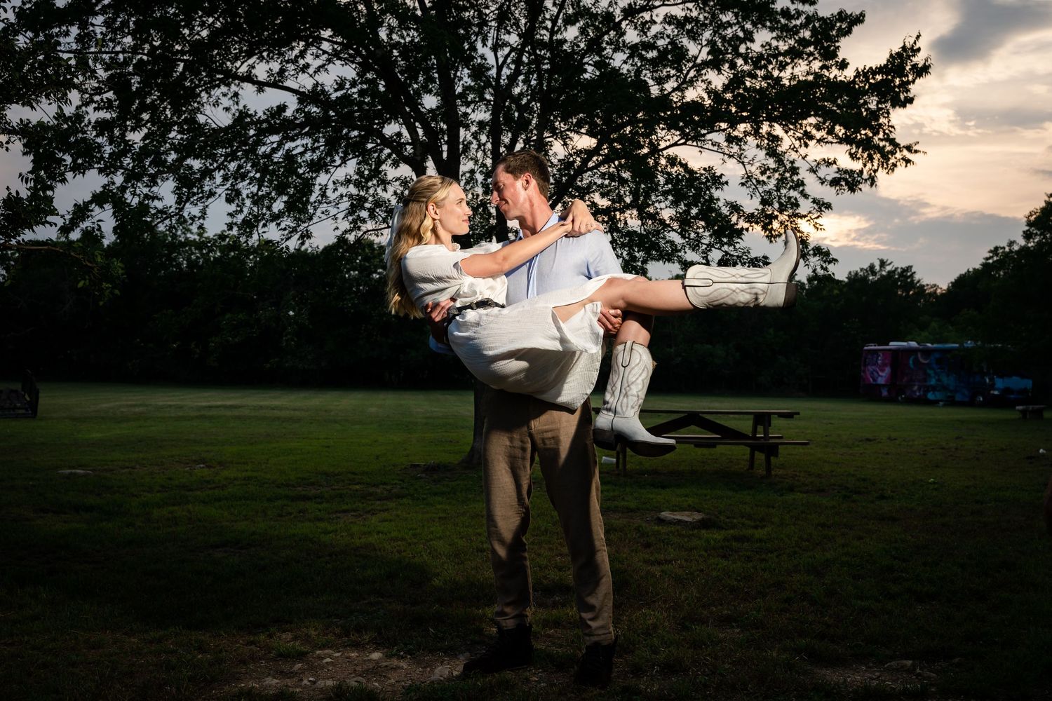 A romantic sunset photo of a couple in a playful pose outdoors.