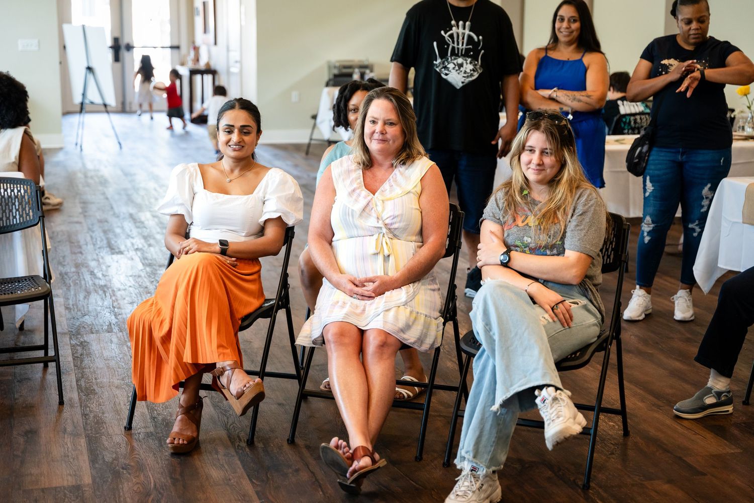 Guests seated in folding chairs at a casual indoor celebration event.