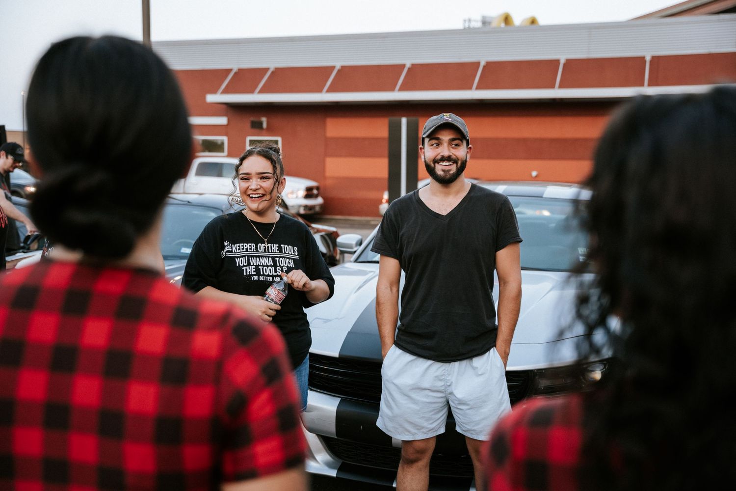Group of people chatting at an outdoor car meet.