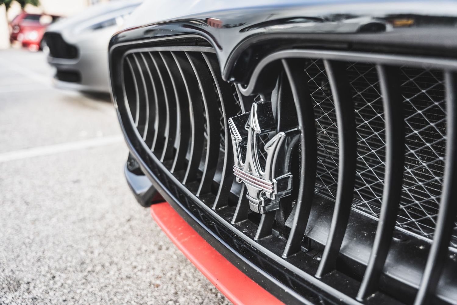 Close-up of Maserati trident logo badge on black mesh grille.