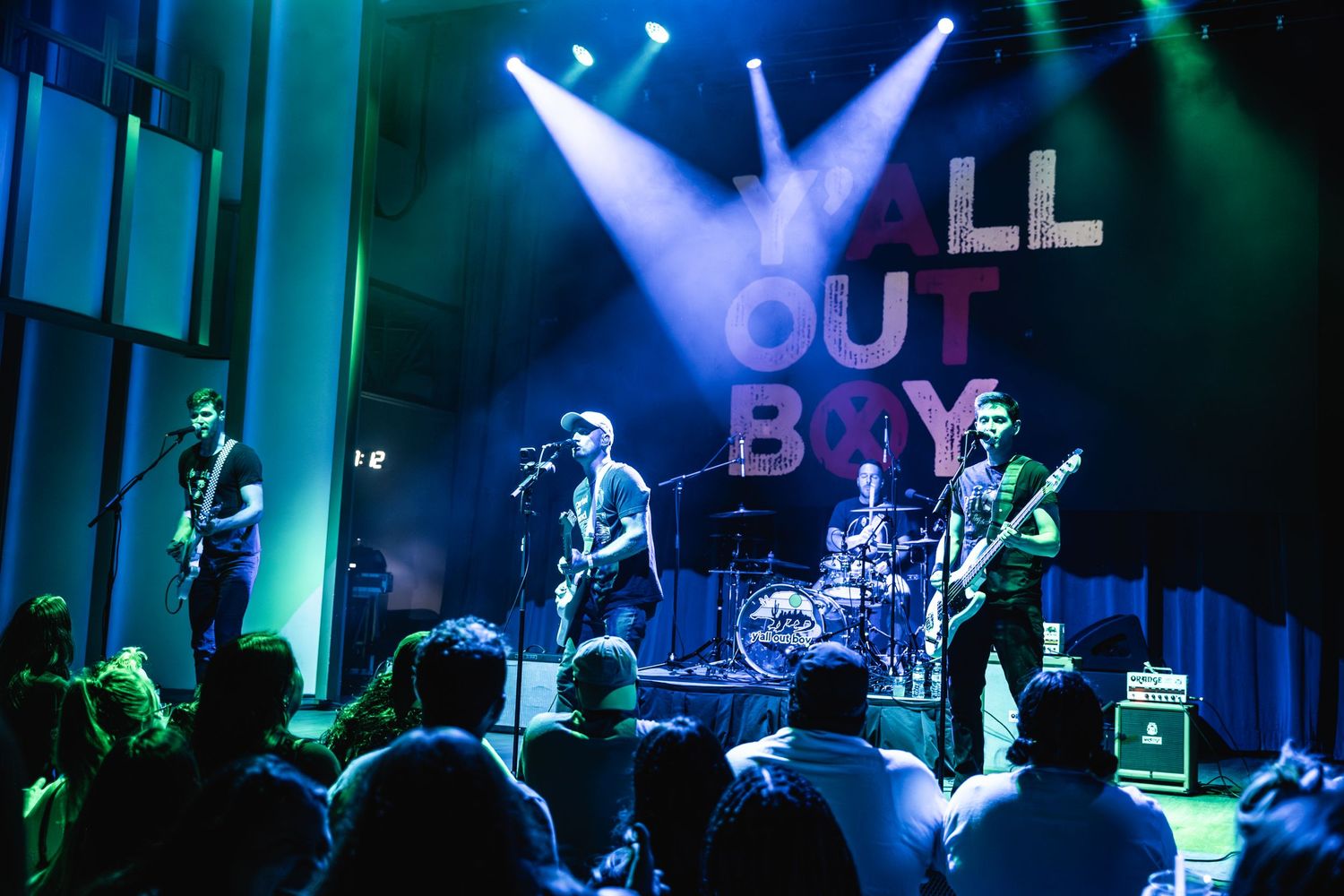 Band performs live under colorful stage lights with Y'all Out Boy logo displayed prominently.