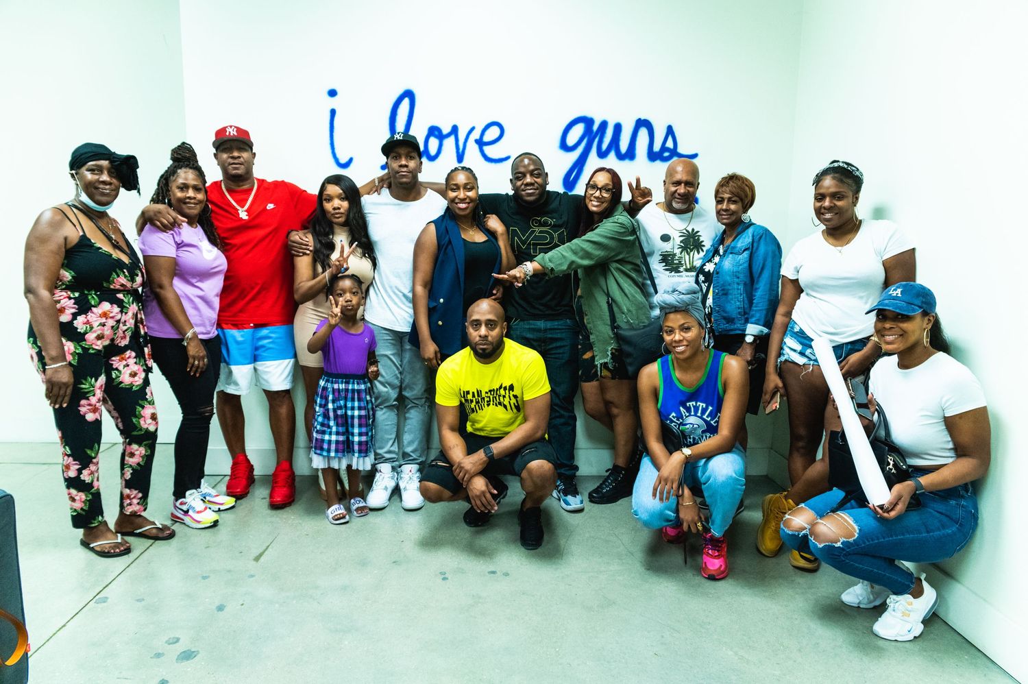 Group photo of shooting range participants posing together in front of blue text wall.