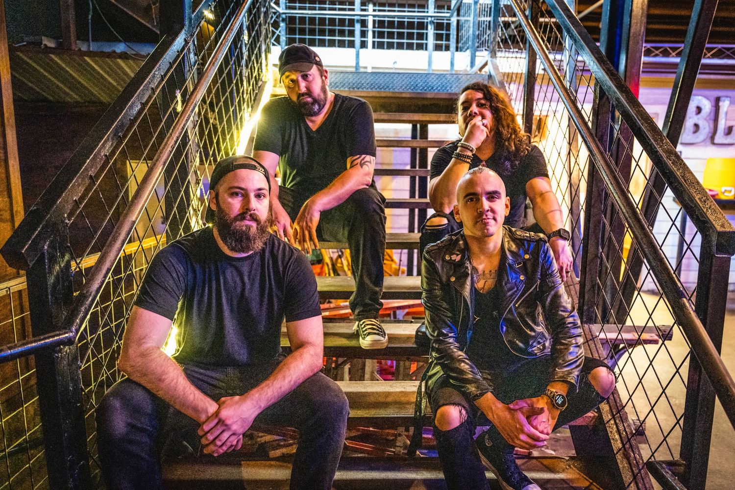 Band members sitting and standing on industrial metal stairs for promotional photo.