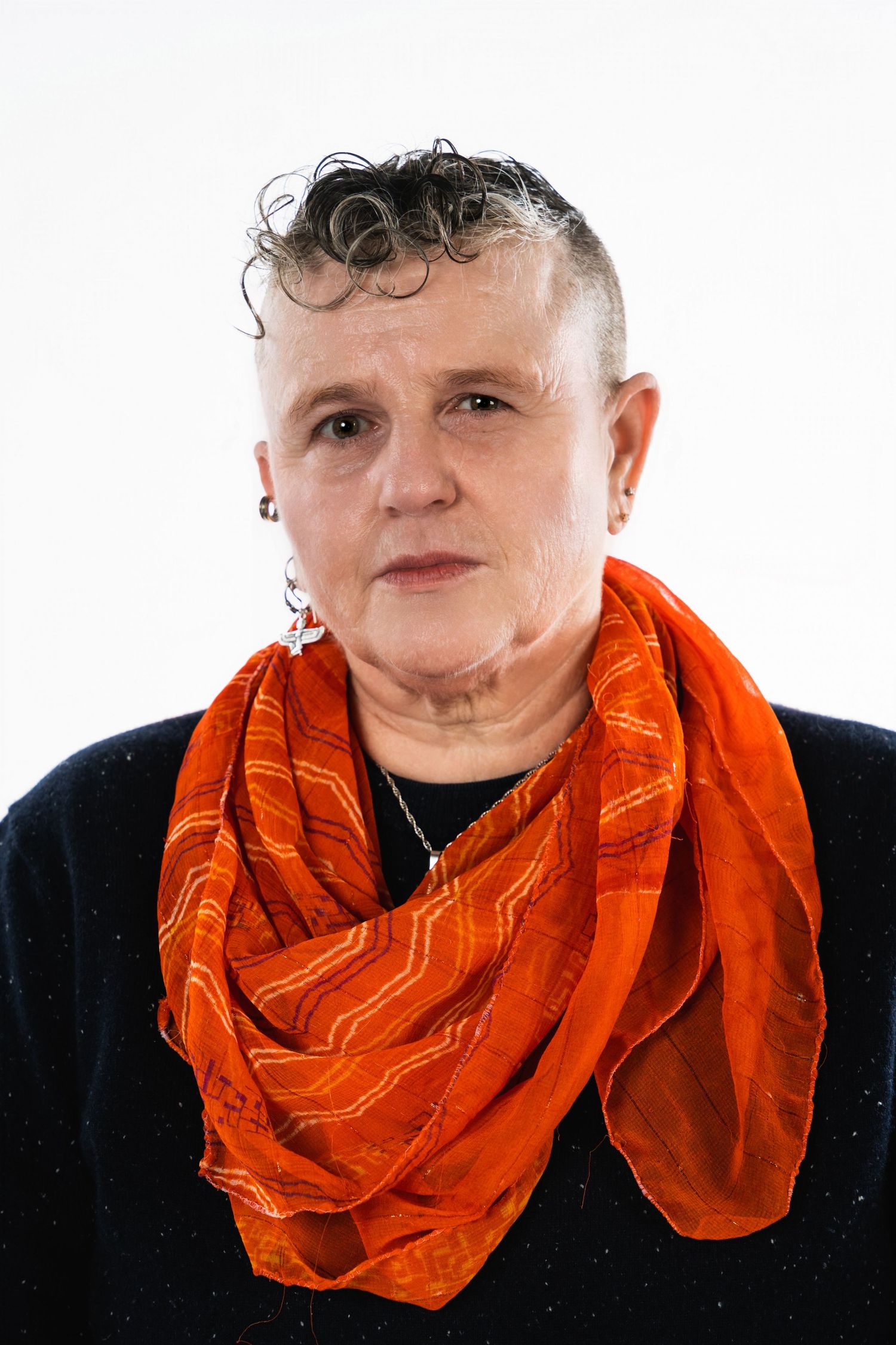 Portrait of a person wearing an orange patterned scarf against a white background.