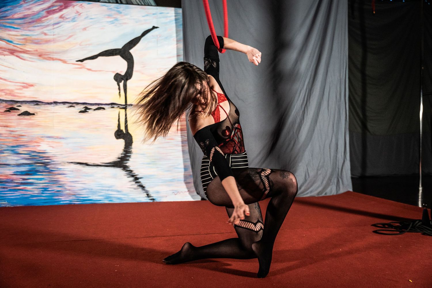 Dynamic aerial performer in black costume during sunset performance.