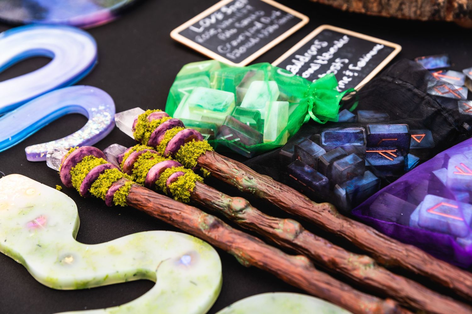 Display of handcrafted magical wands and mystical accessories on a dark surface.