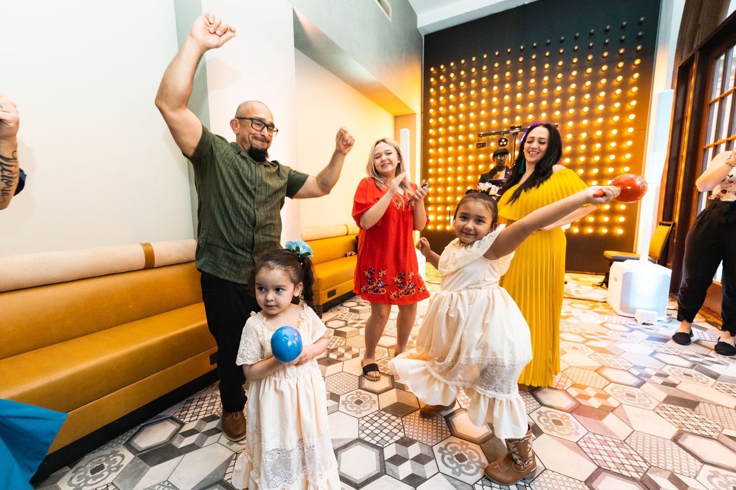 People dancing and celebrating together in a venue with distinctive geometric floor patterns.