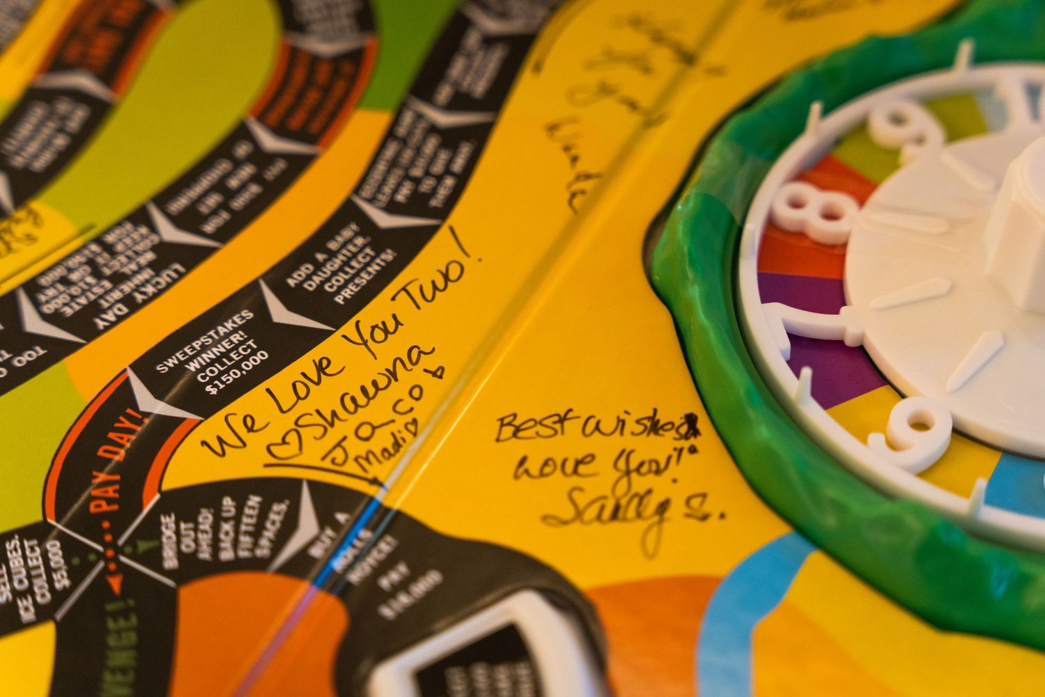 Close-up of colorful board game pieces and handwritten notes on yellow surface.