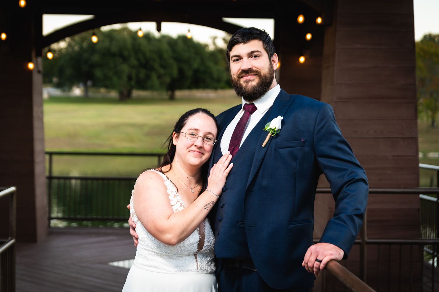 Happy couple sharing a tender moment under a gazebo with string lights and golf course view.