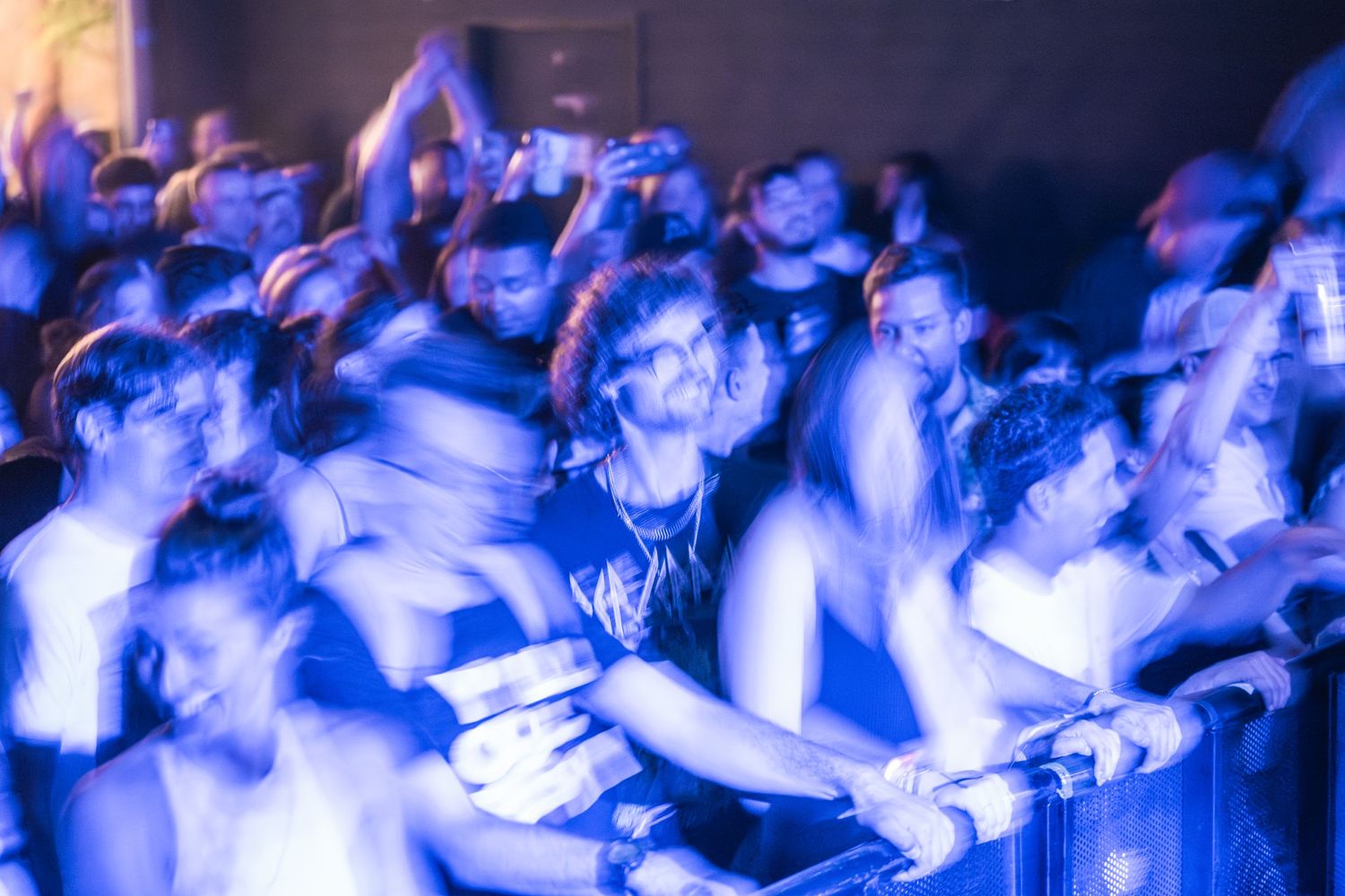 Blurred crowd of concert-goers illuminated by blue stage lights during live performance.