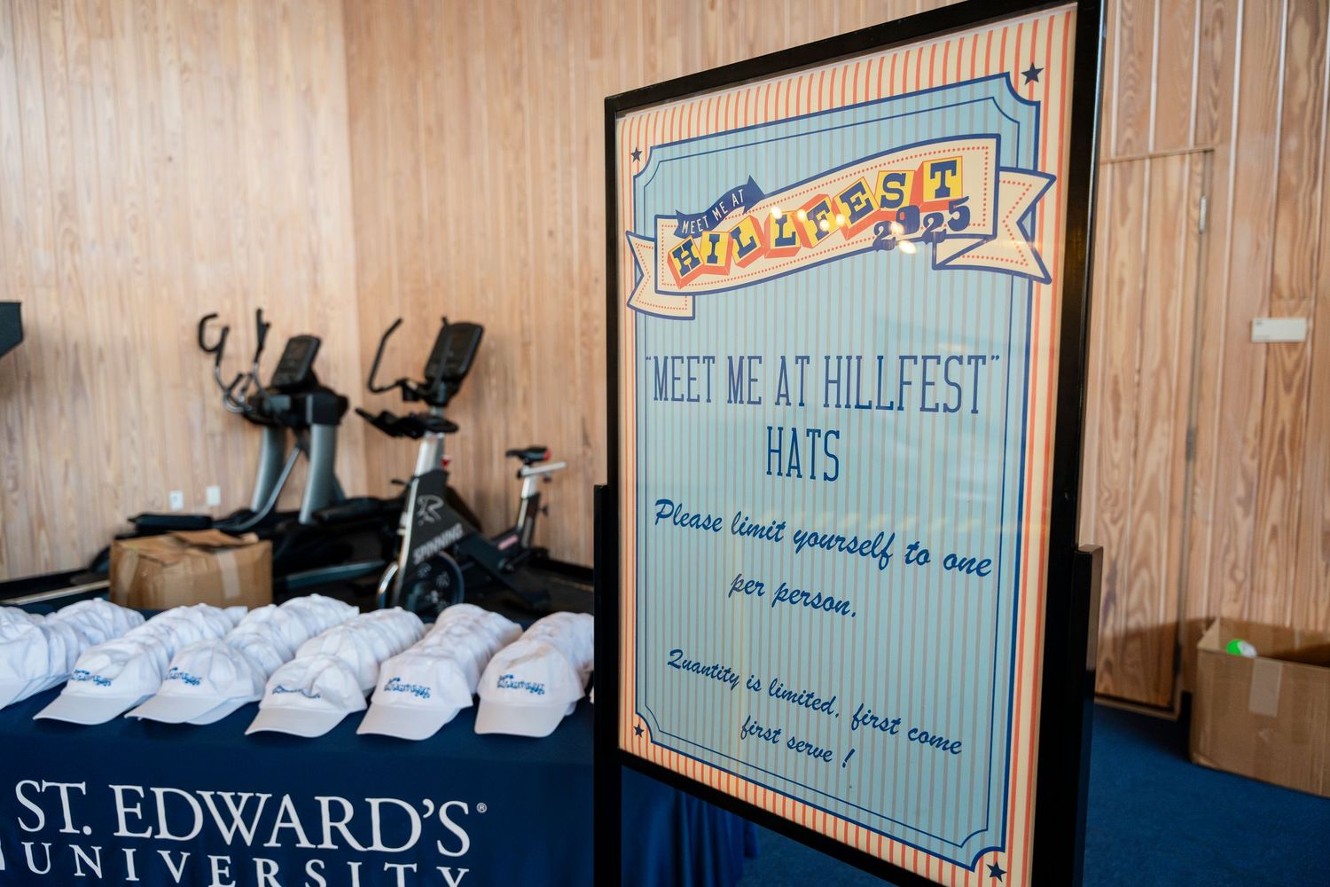 A vintage-style welcome sign near folded t-shirts and St. Edwards University merchandise displays.