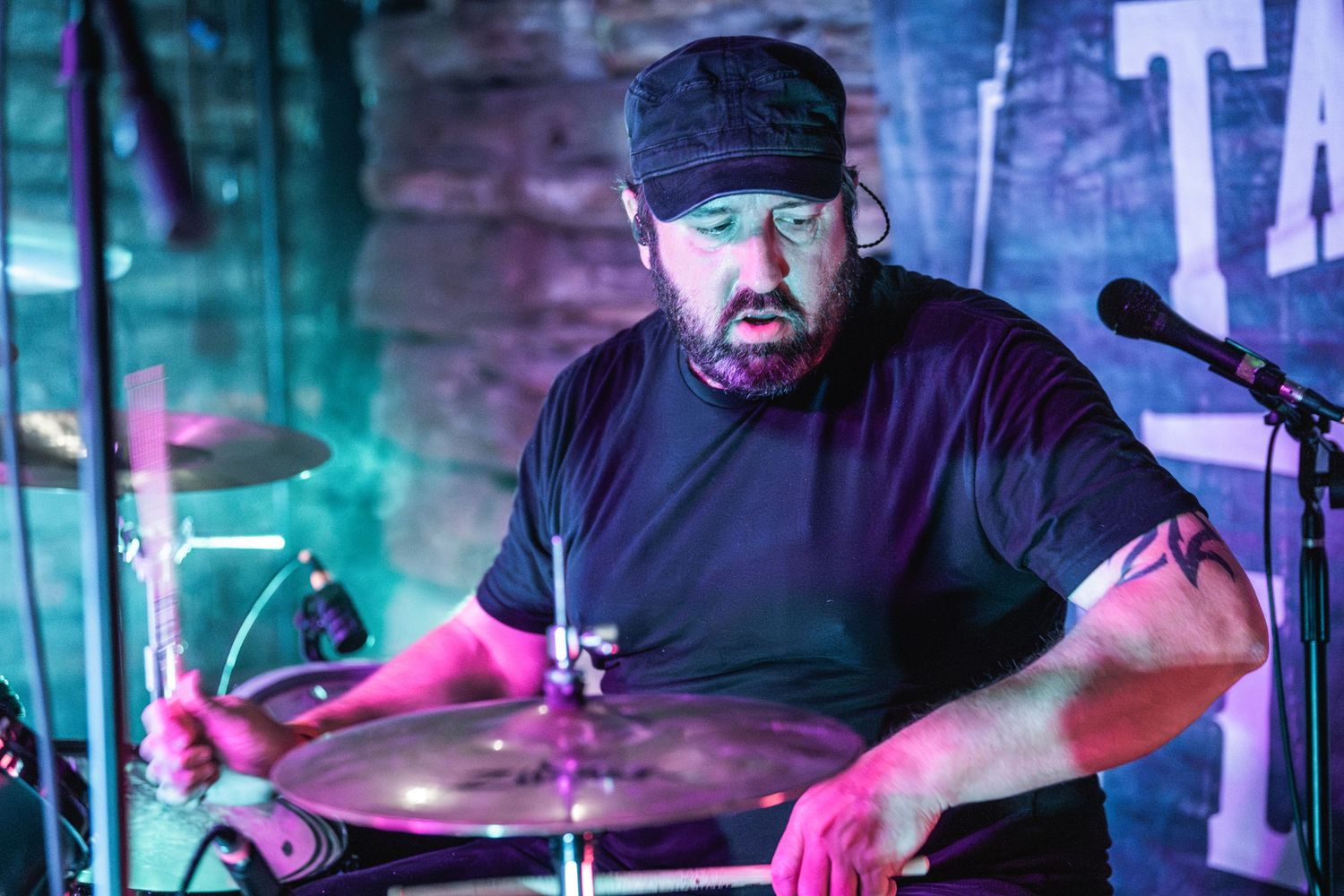 Drummer performing with dramatic blue and pink stage lighting.