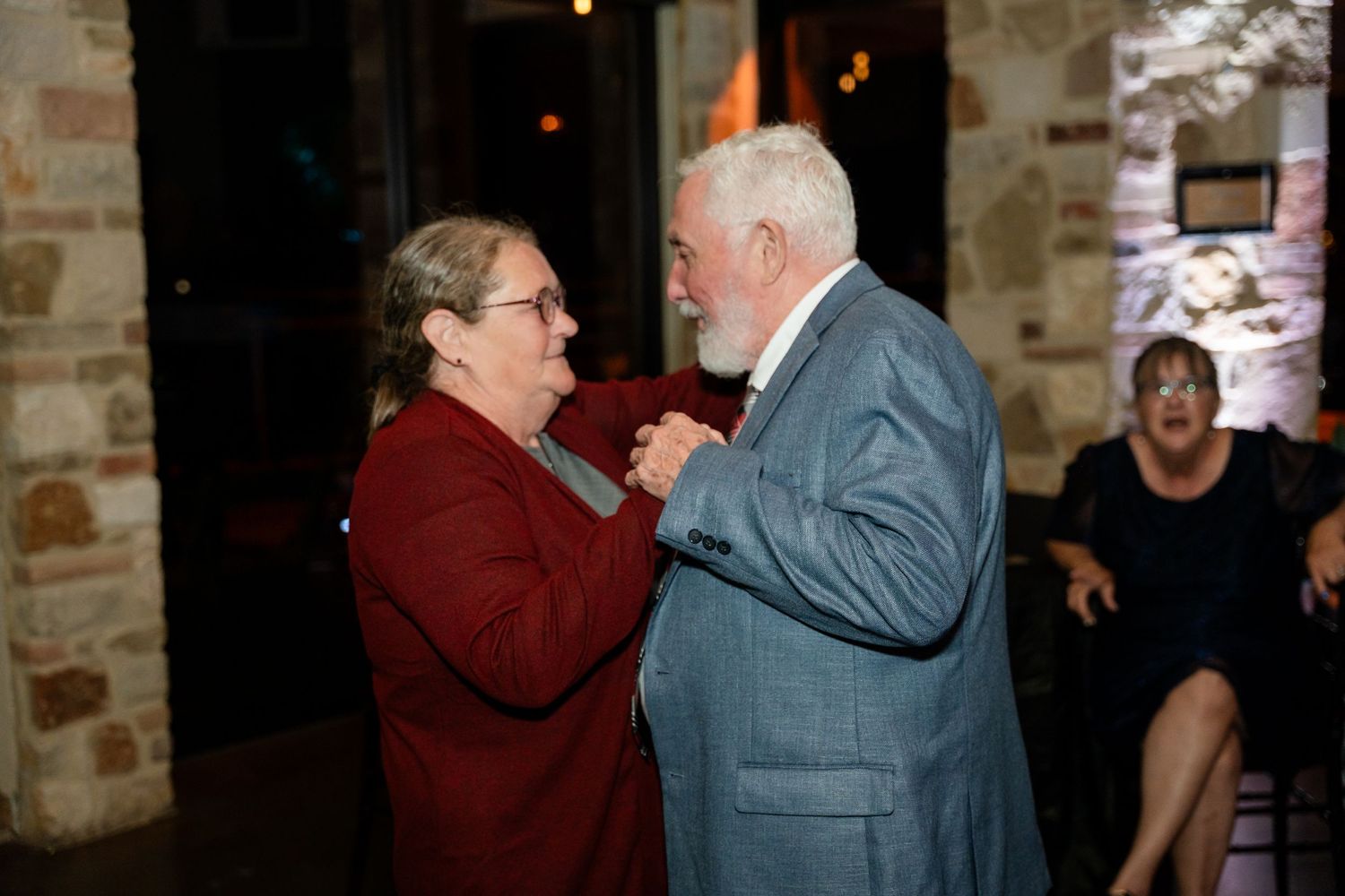 A couple shares a tender dance moment in warm lighting at an indoor venue.