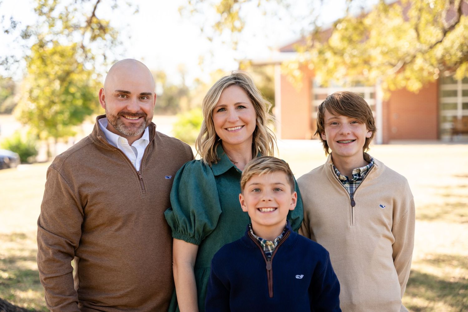 Family portrait taken outside during golden hour with brick building in background.