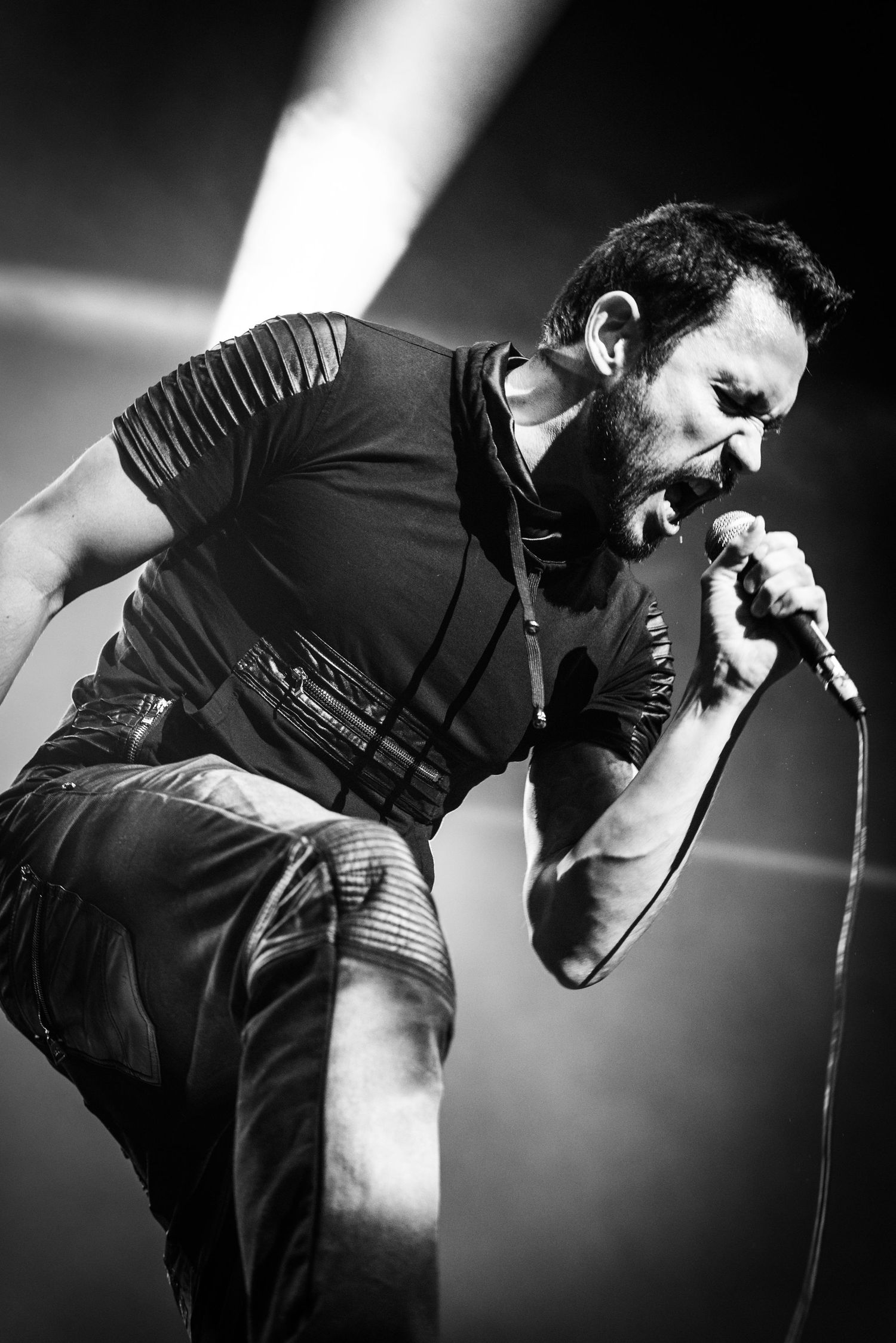 Black and white concert photo captures intense vocal performance with dramatic lighting.