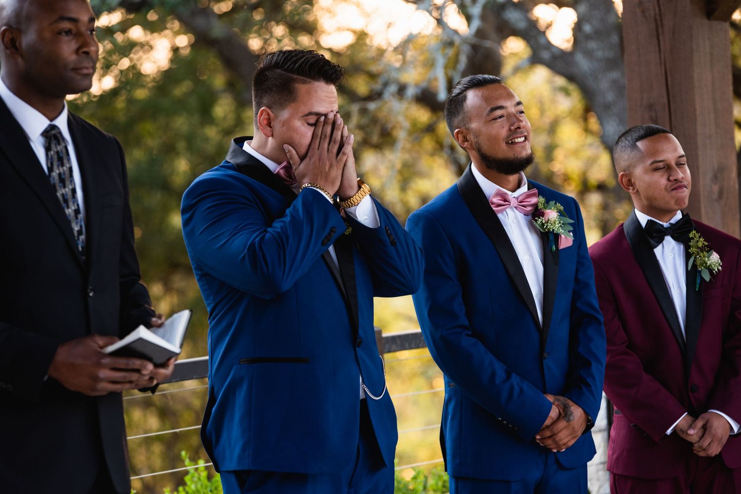 Emotional wedding ceremony moment with groomsmen in blue and burgundy suits.