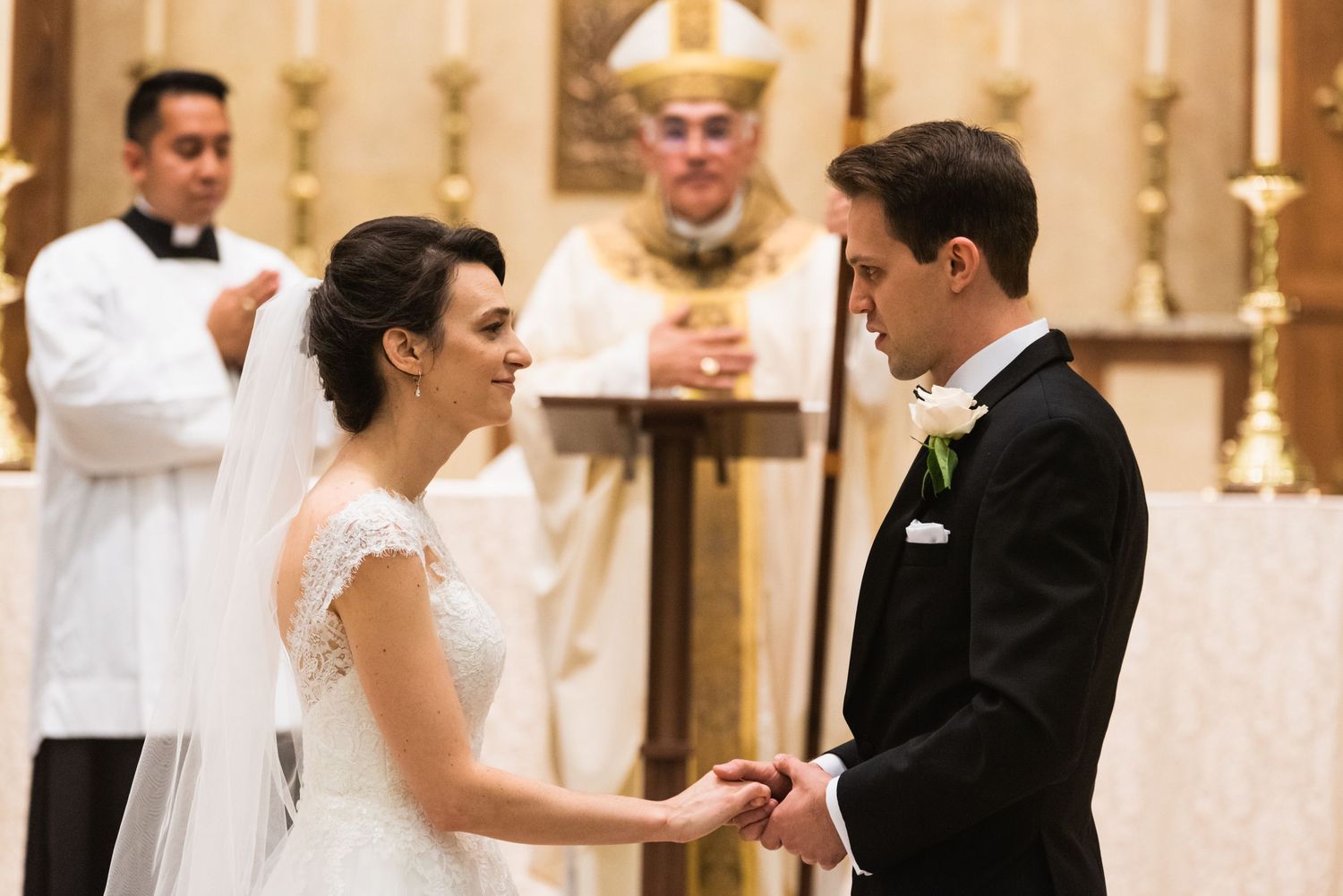Wedding ceremony with couple exchanging rings at altar with priest officiating.