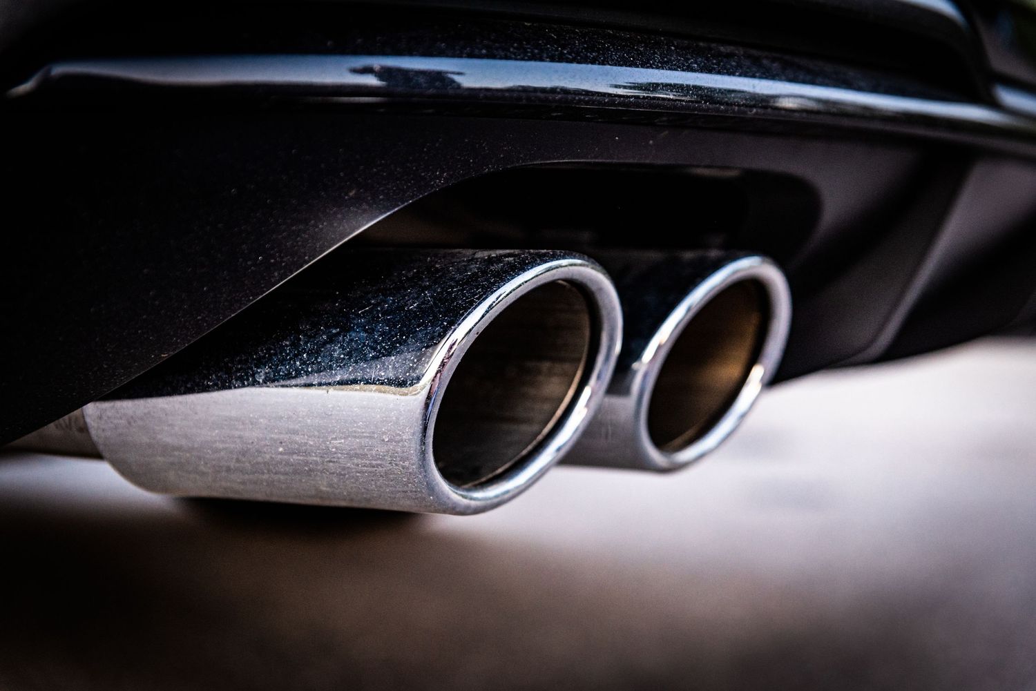 Close up of dual chrome exhaust tips on black Audi performance vehicle.