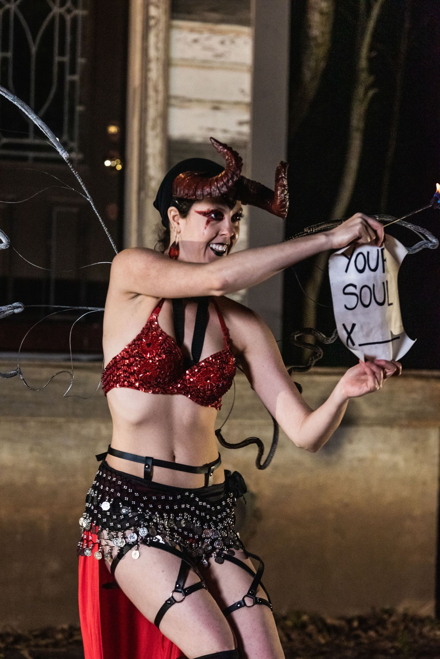 Burlesque performer in red sequined costume holds prop during theatrical performance.