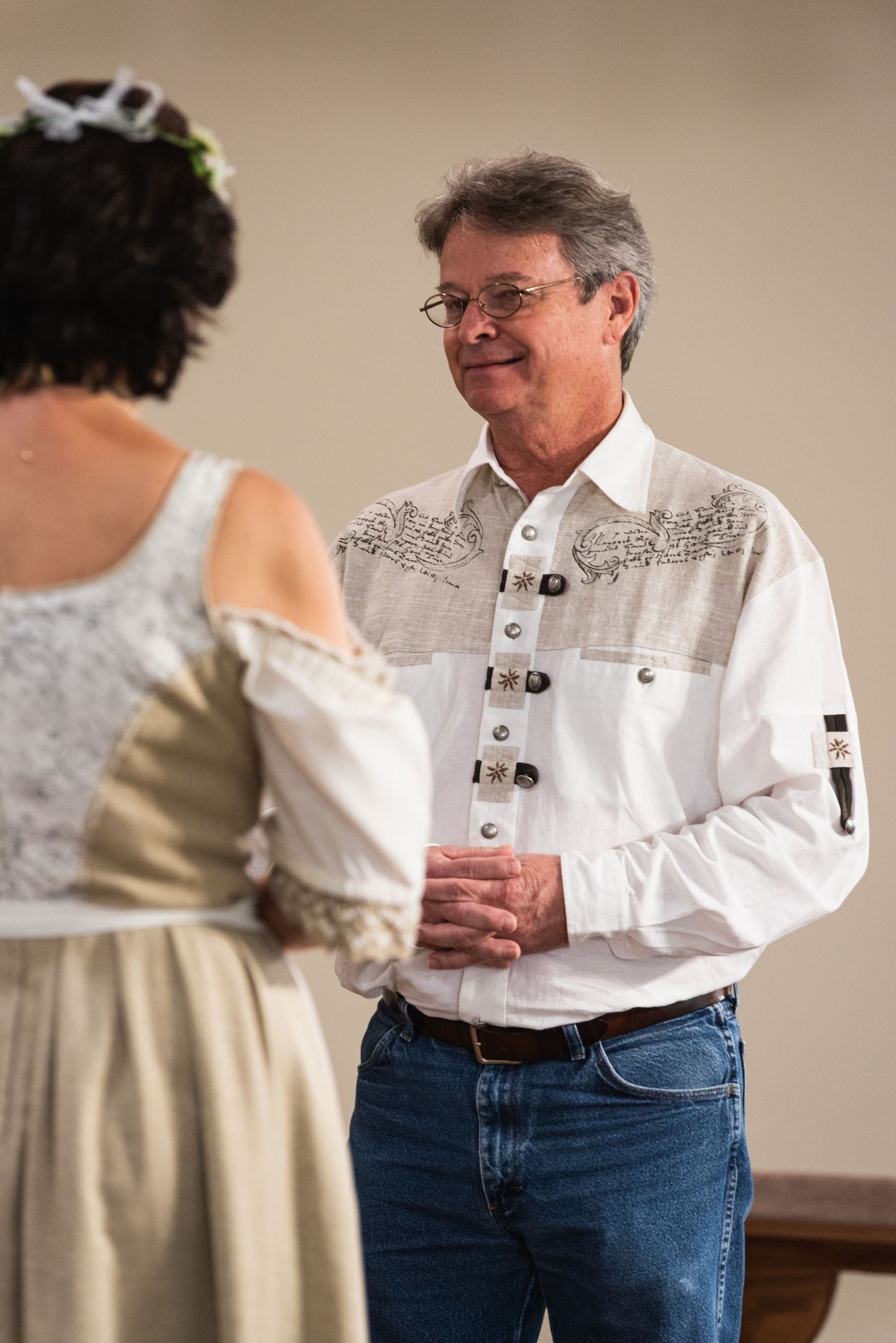 Person in white embroidered shirt and jeans interacting during a ceremony.