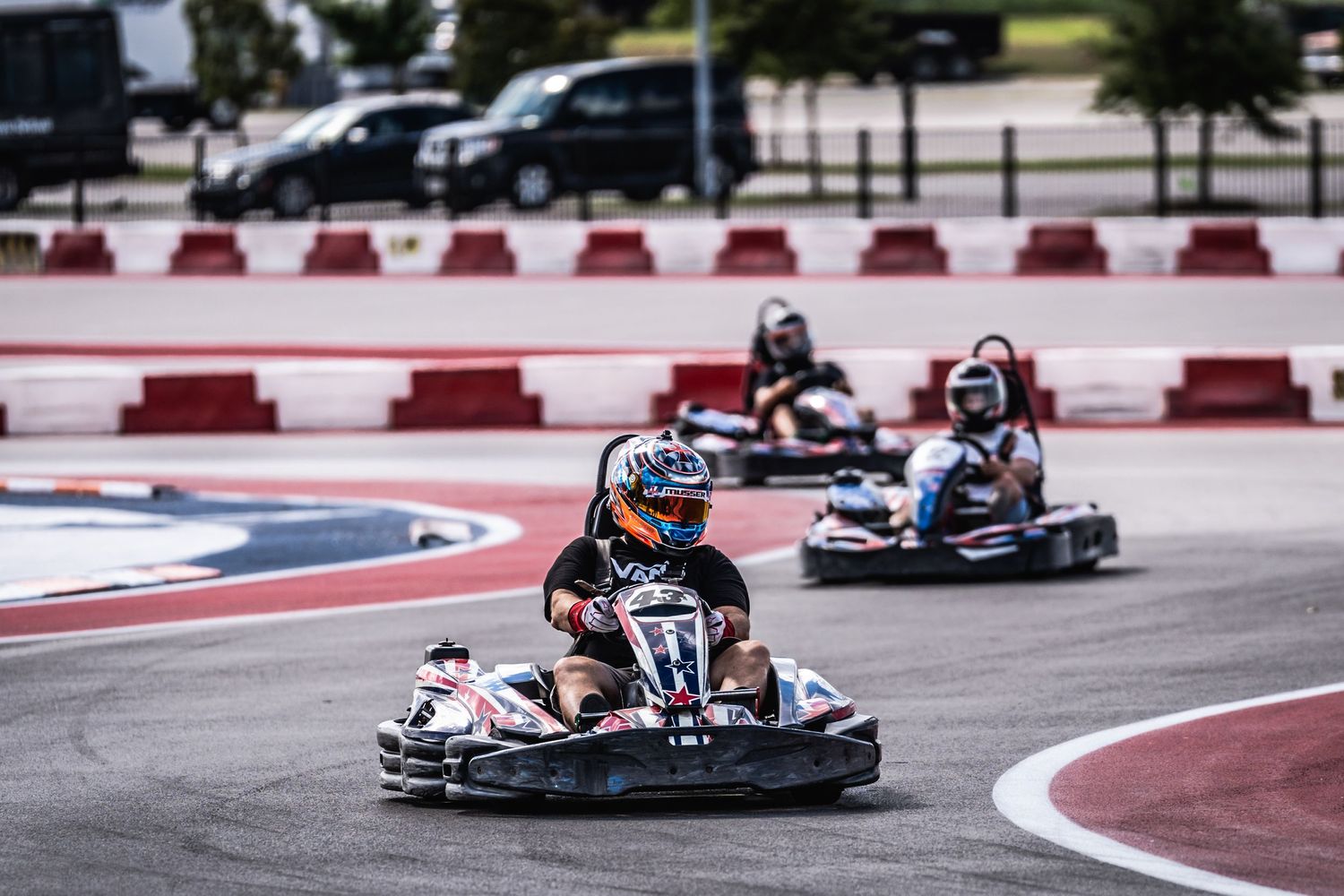 Three go-karts racing in formation on professional karting circuit.