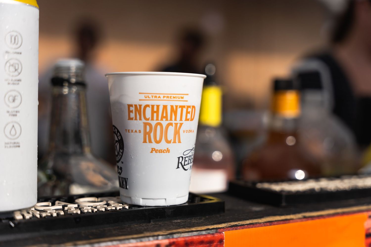 A branded paper cup with 'Enchanted Rock' text sits on a dark surface.