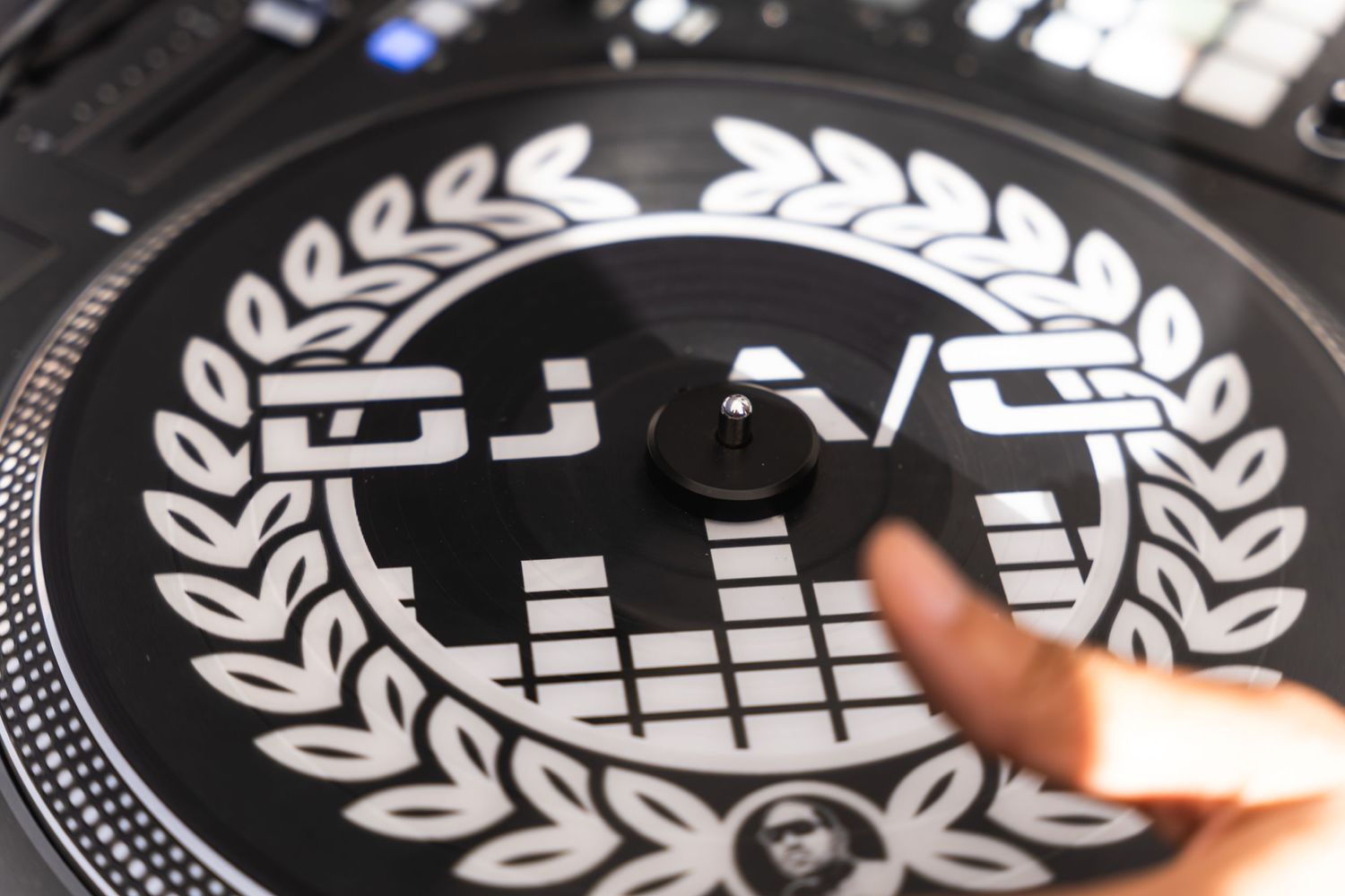 Close-up of a DJ turntable with a decorative laurel wreath logo design.