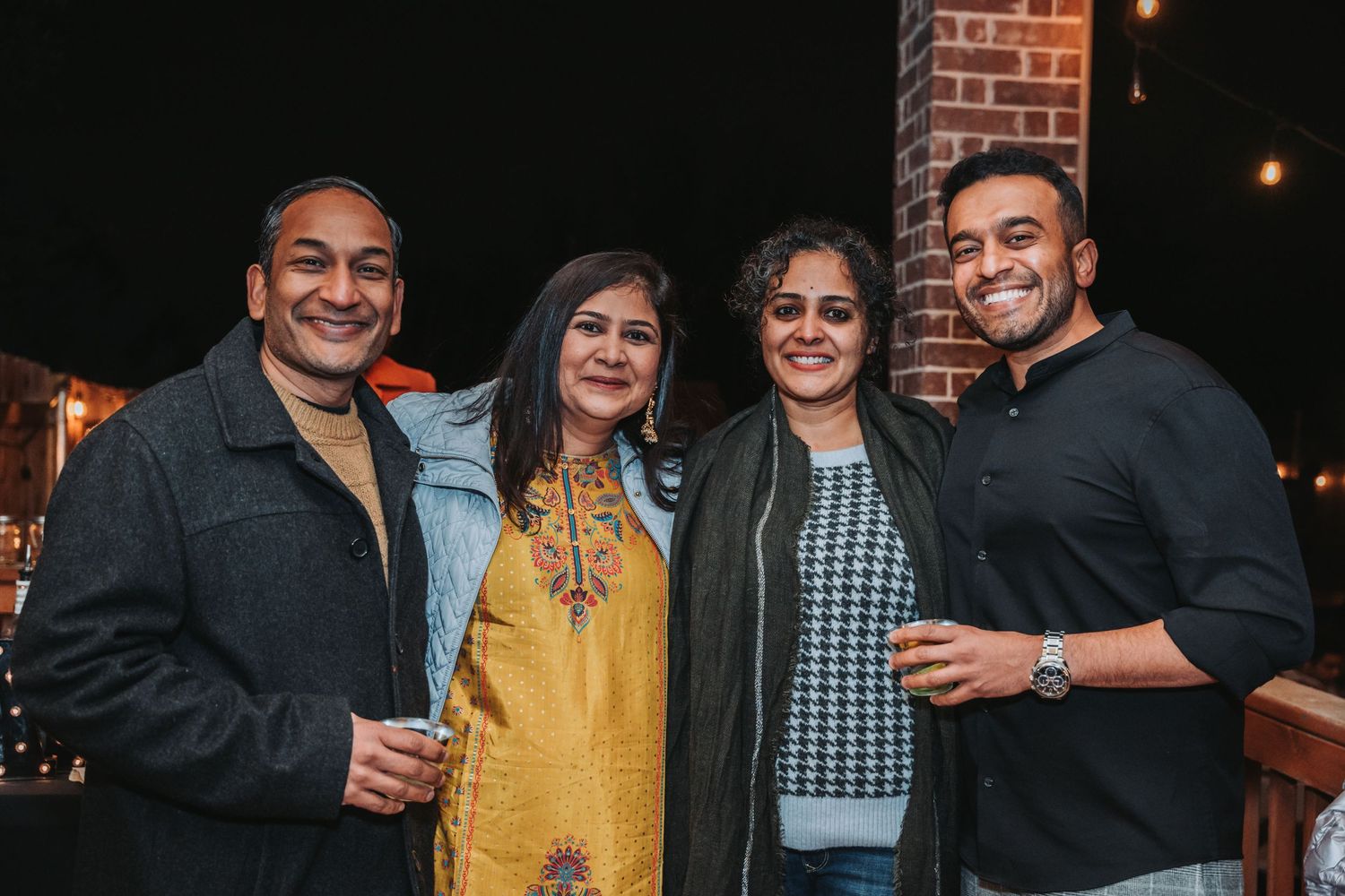 Small group gathered for a friendly photo during an evening outdoor celebration.