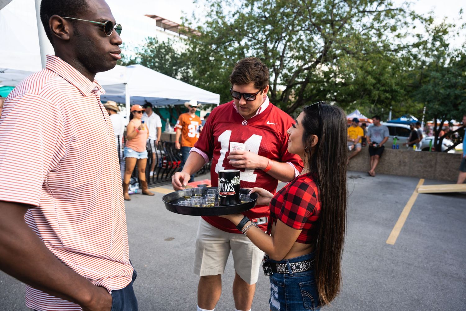 Game day attendees share drinks and conversation at an outdoor tailgate event.
