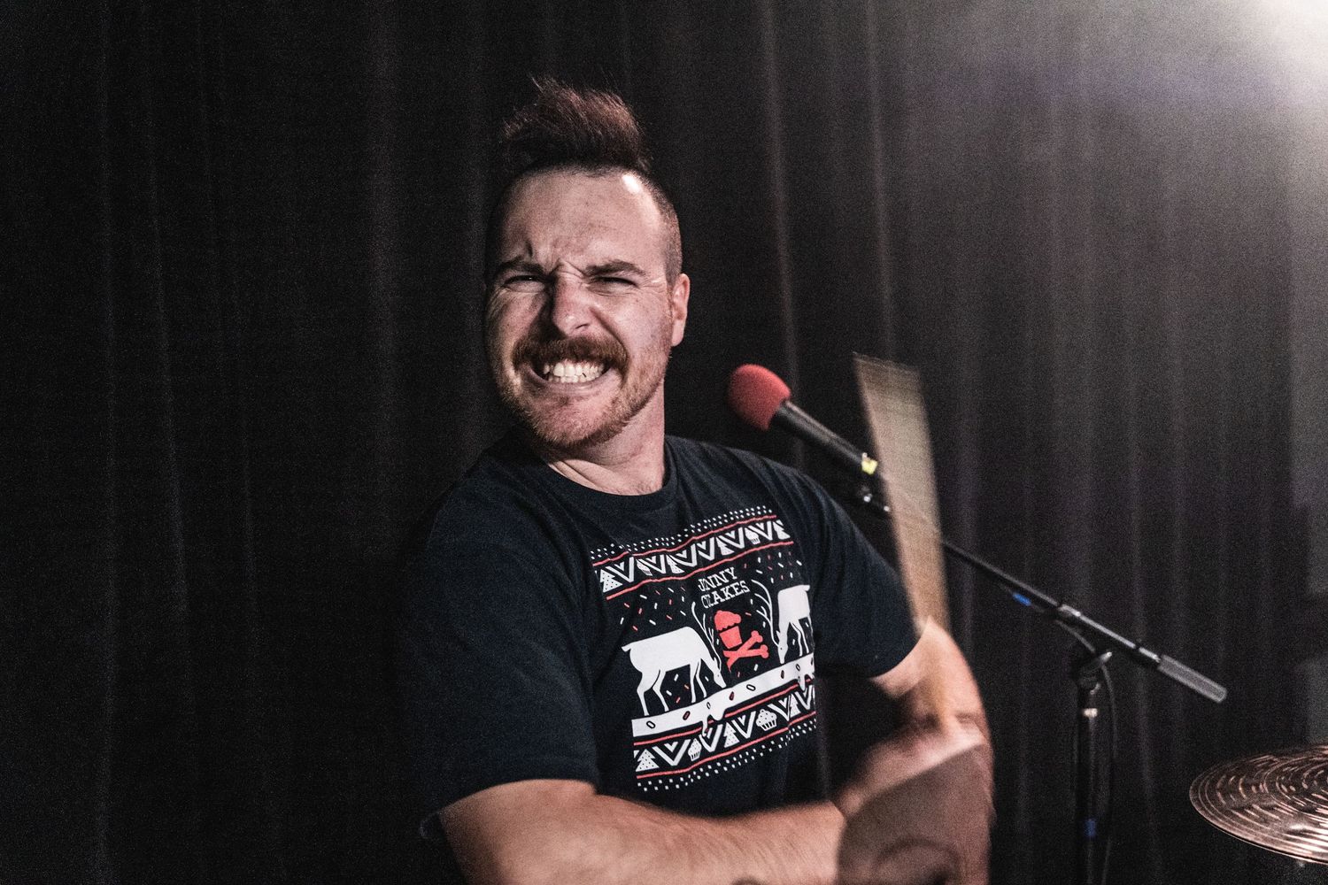 A performer on stage captured in an enthusiastic moment under bright stage lights.