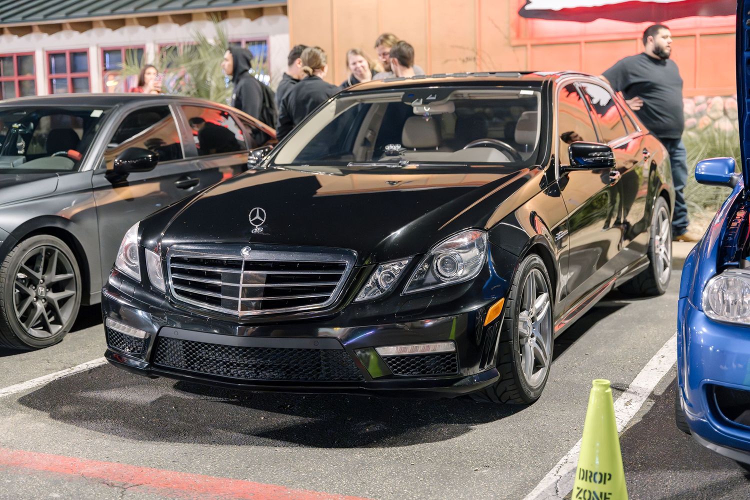 A sleek black Mercedes-Benz E-Class sedan parked at a car meet.
