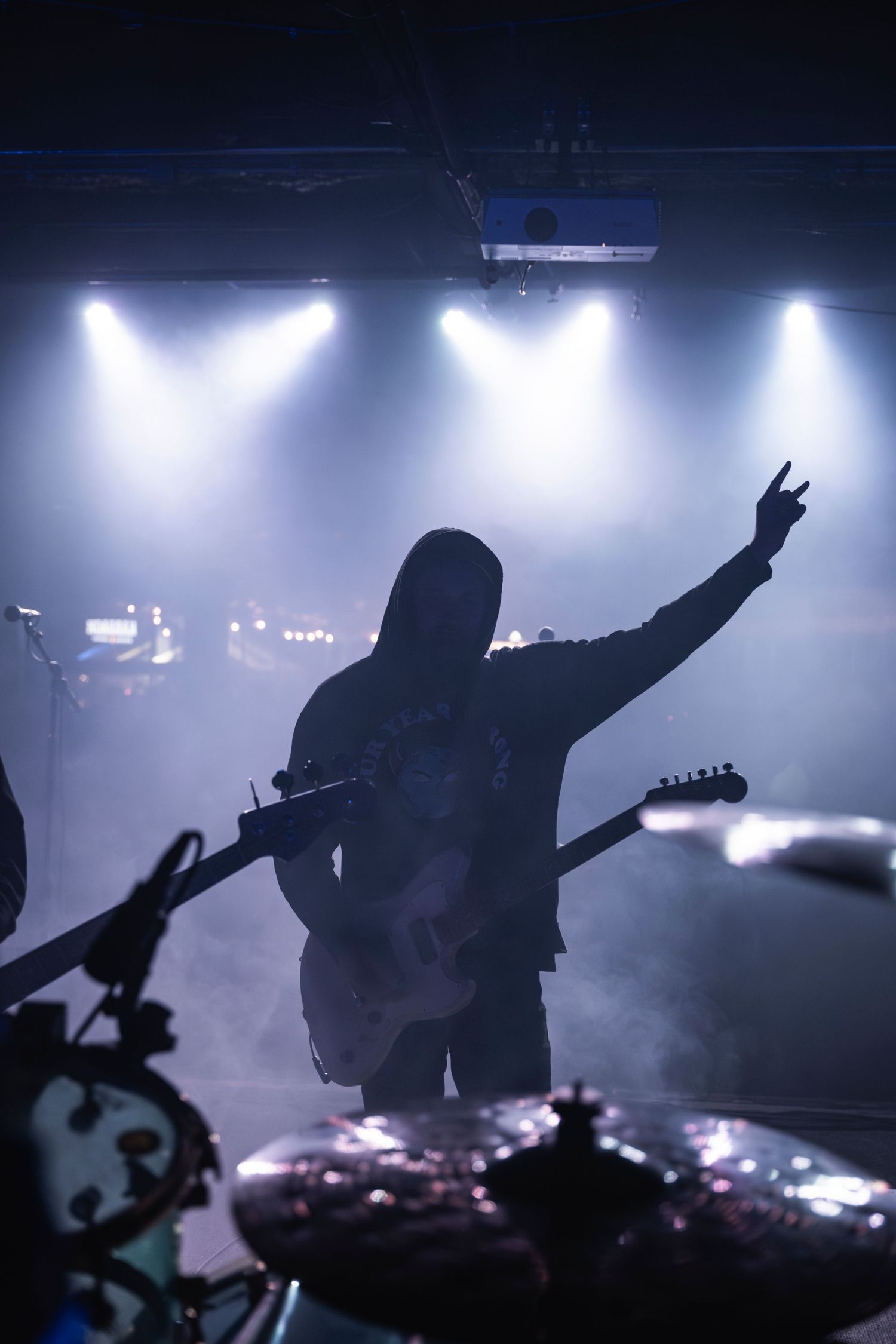 Silhouetted guitarist performing on stage with dramatic backlighting and fog effects during rock concert.