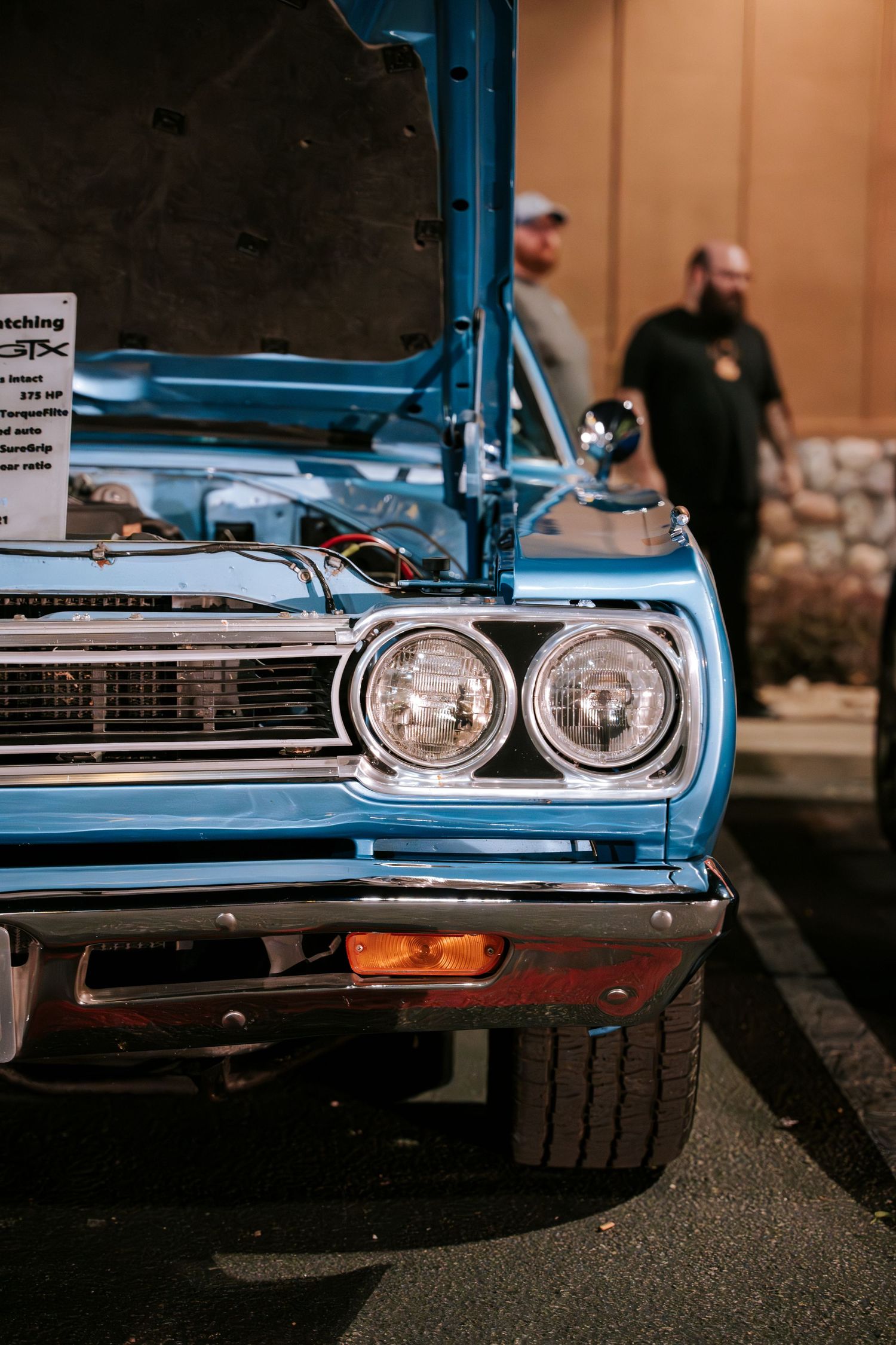 Close up of vintage blue muscle car headlights at a car show.
