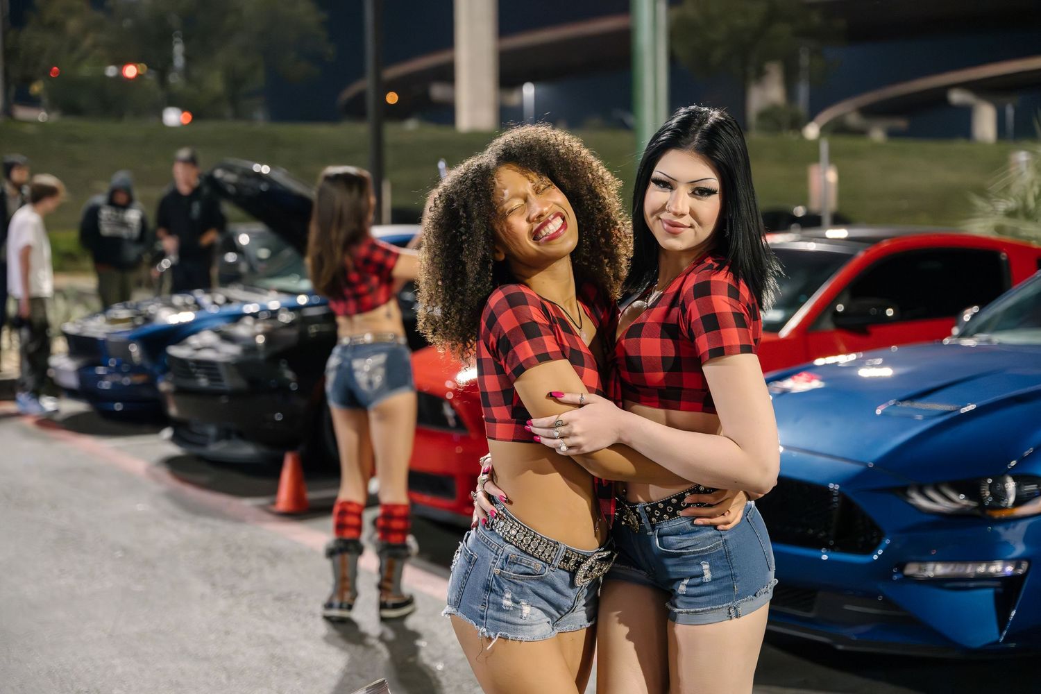 Car enthusiasts gathered at outdoor nighttime automotive event.