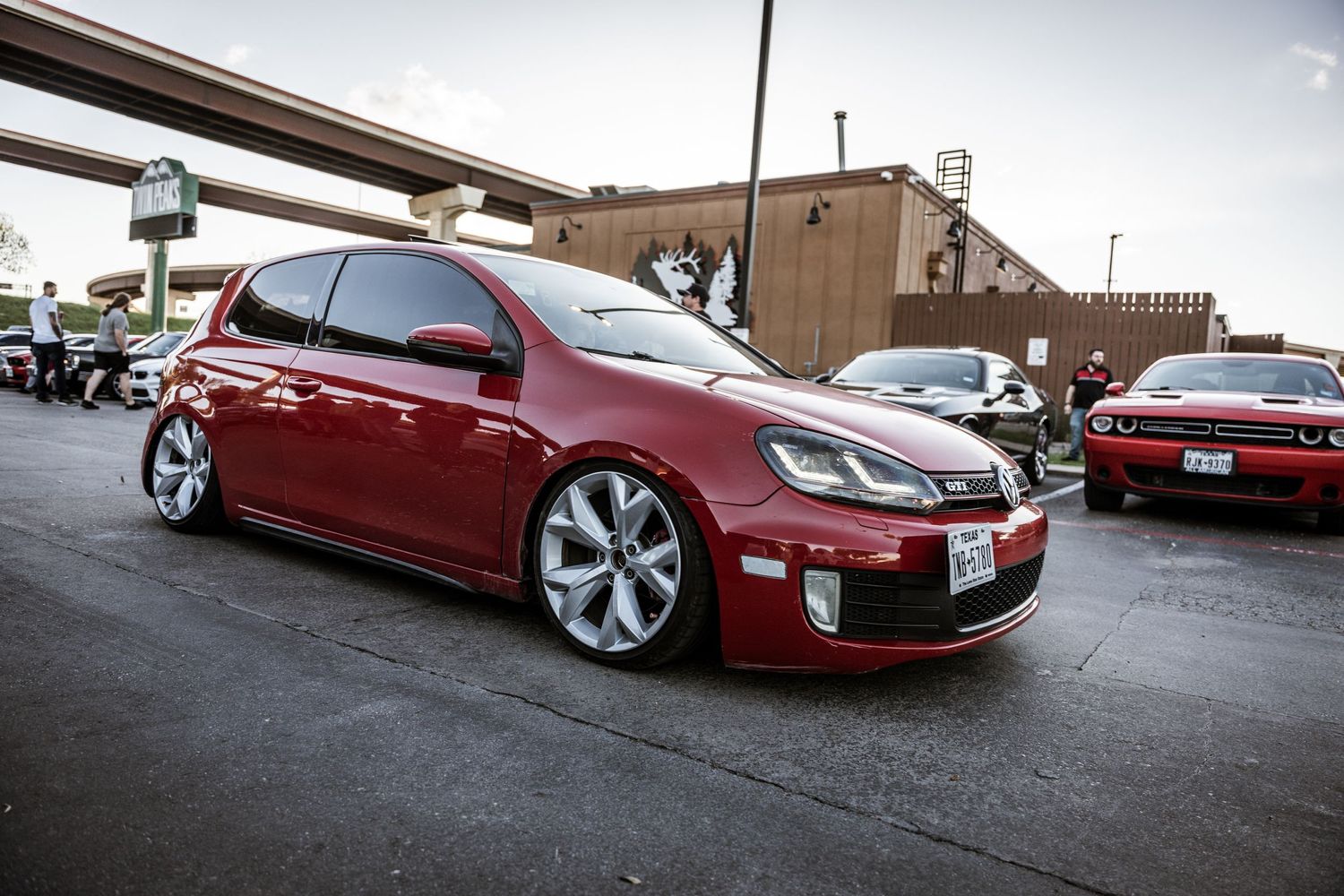 Lowered red Volkswagen GTI with custom wheels photographed at an angle.
