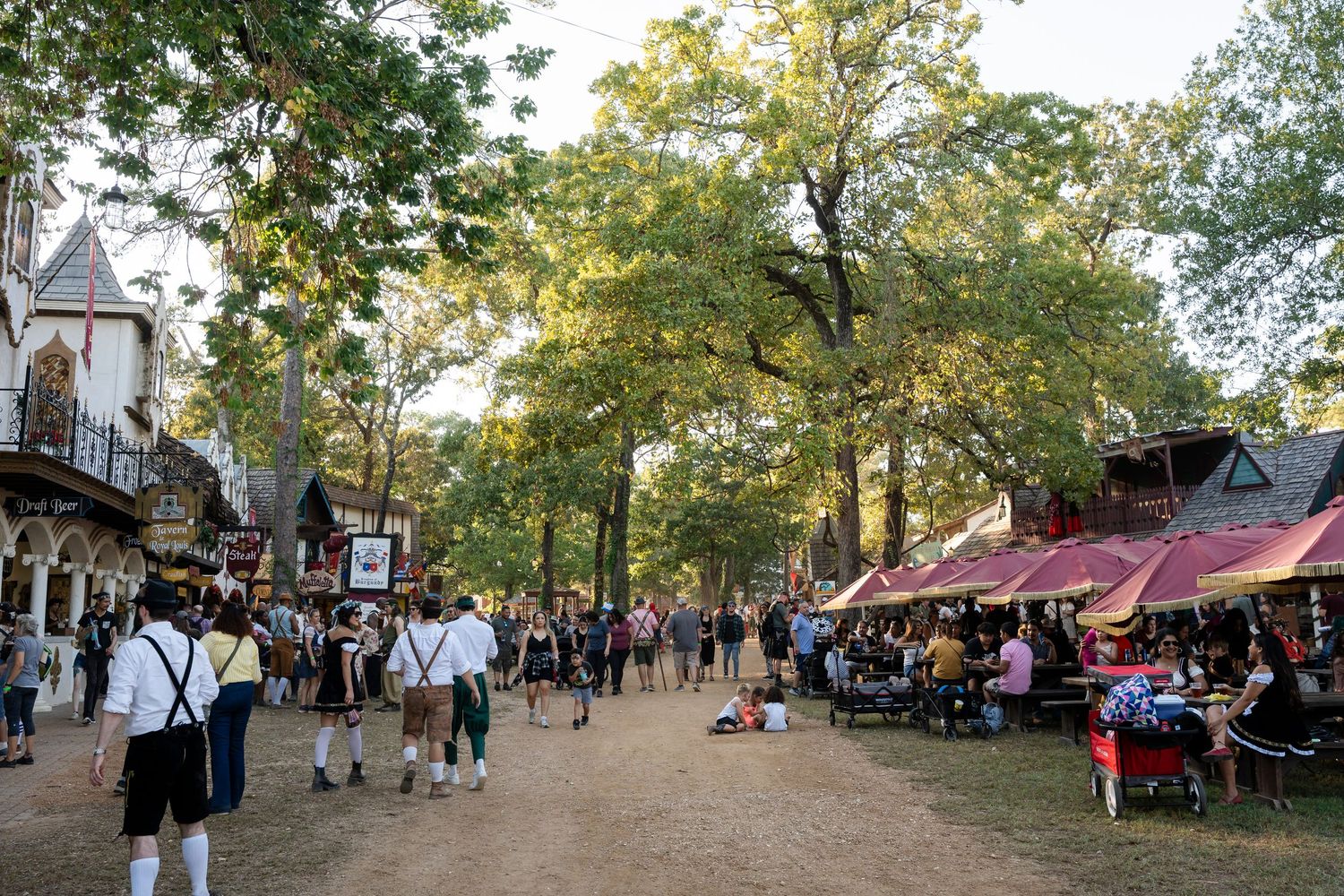 A panoramic sequence of outdoor festival scenes showing vendor stalls and crowds gathered under trees at a community event.
