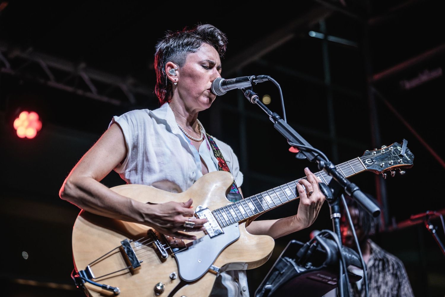 Musicians perform on stage with guitars and bass during a live concert performance.