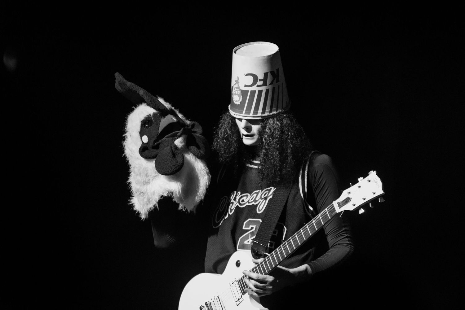 A person plays an electric guitar on stage during a live performance with dramatic lighting effects.