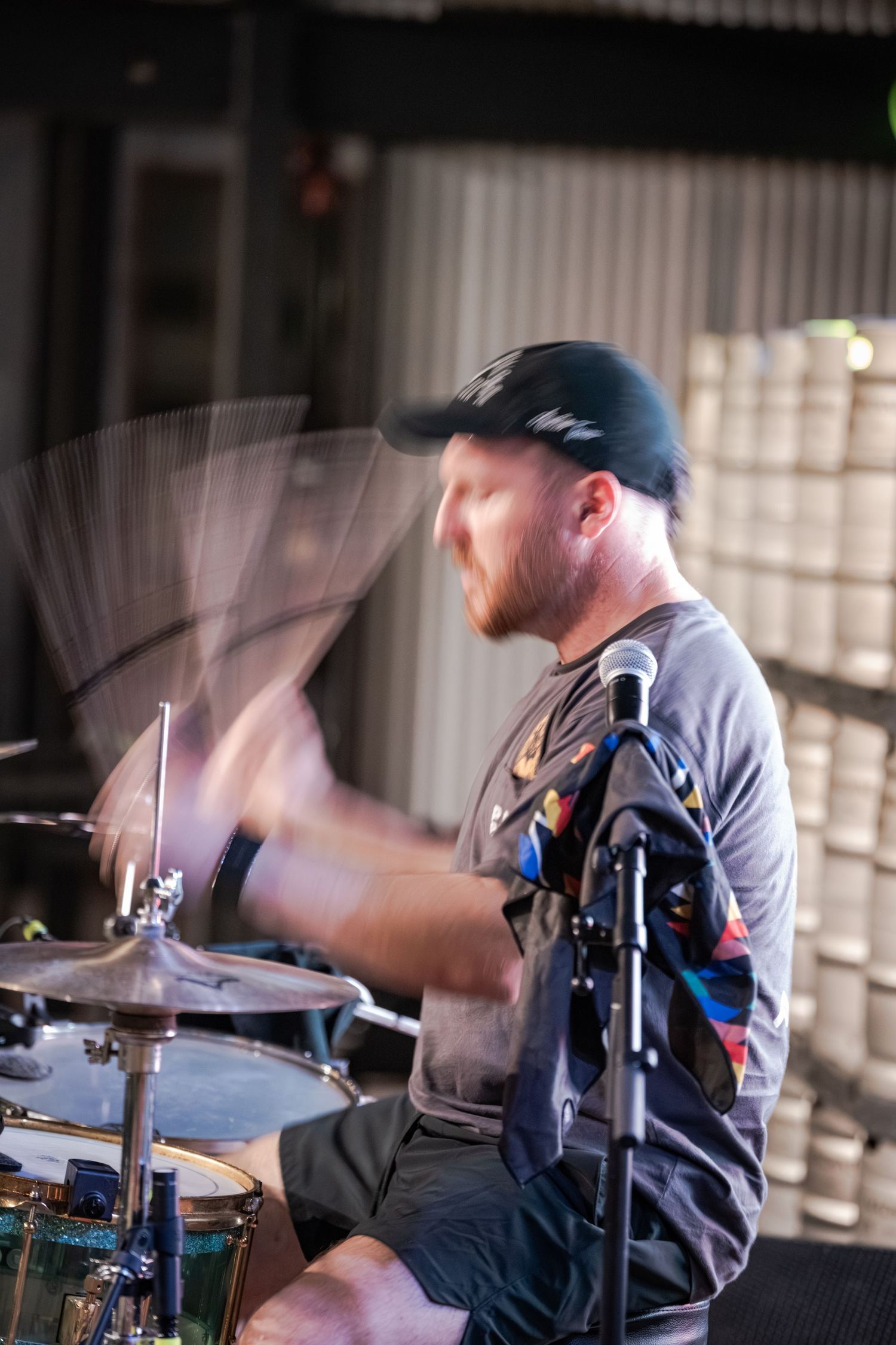 A drummer passionately plays cymbals with motion blur effect captured during a live outdoor performance.