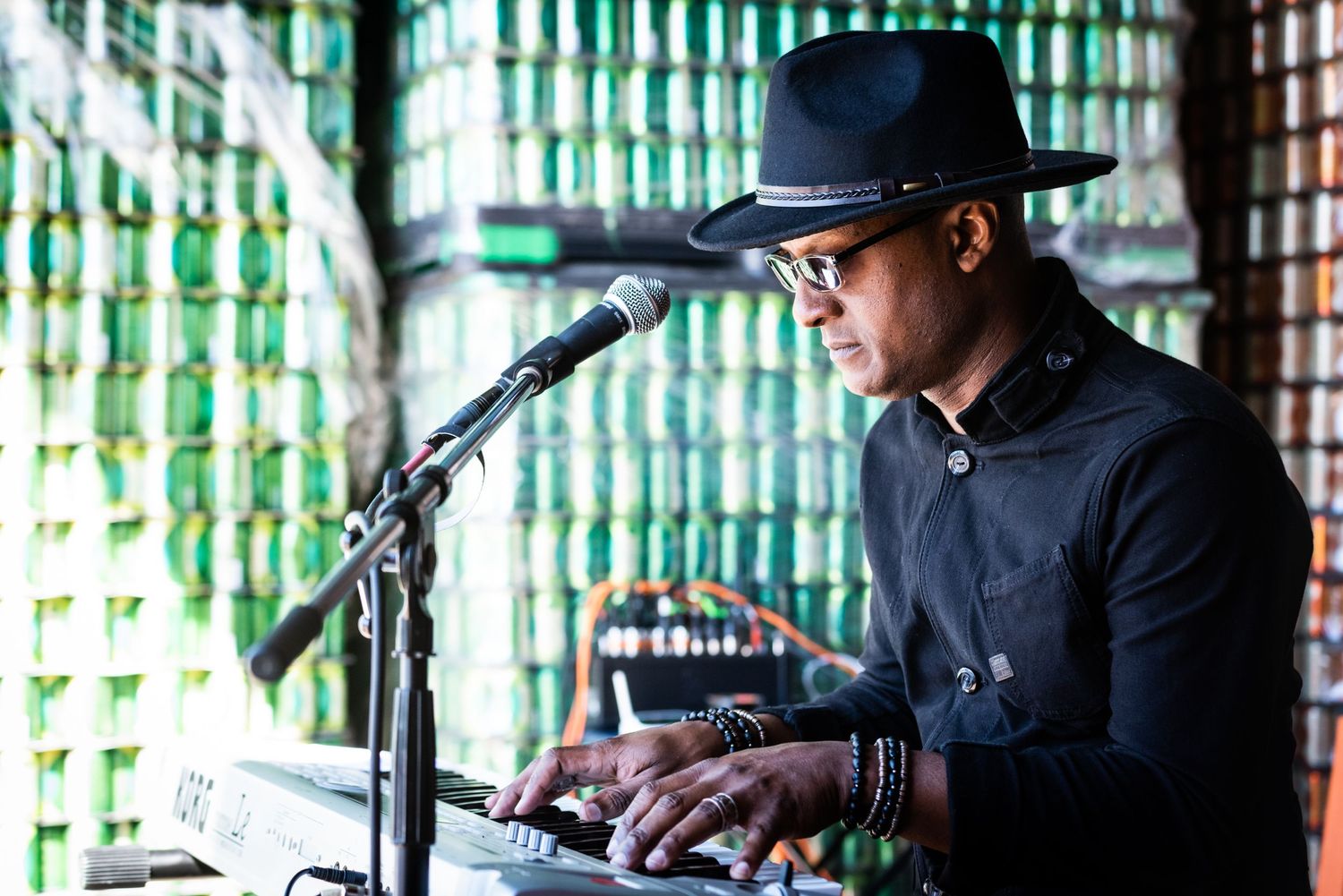DJ performing at an event with green bottle wall backdrop.