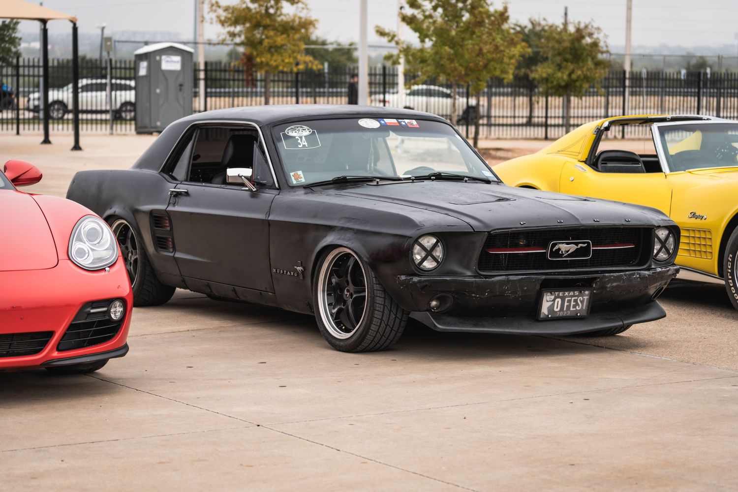 Modified black Ford Mustang with custom wheels and lowered suspension parked at a car show event.