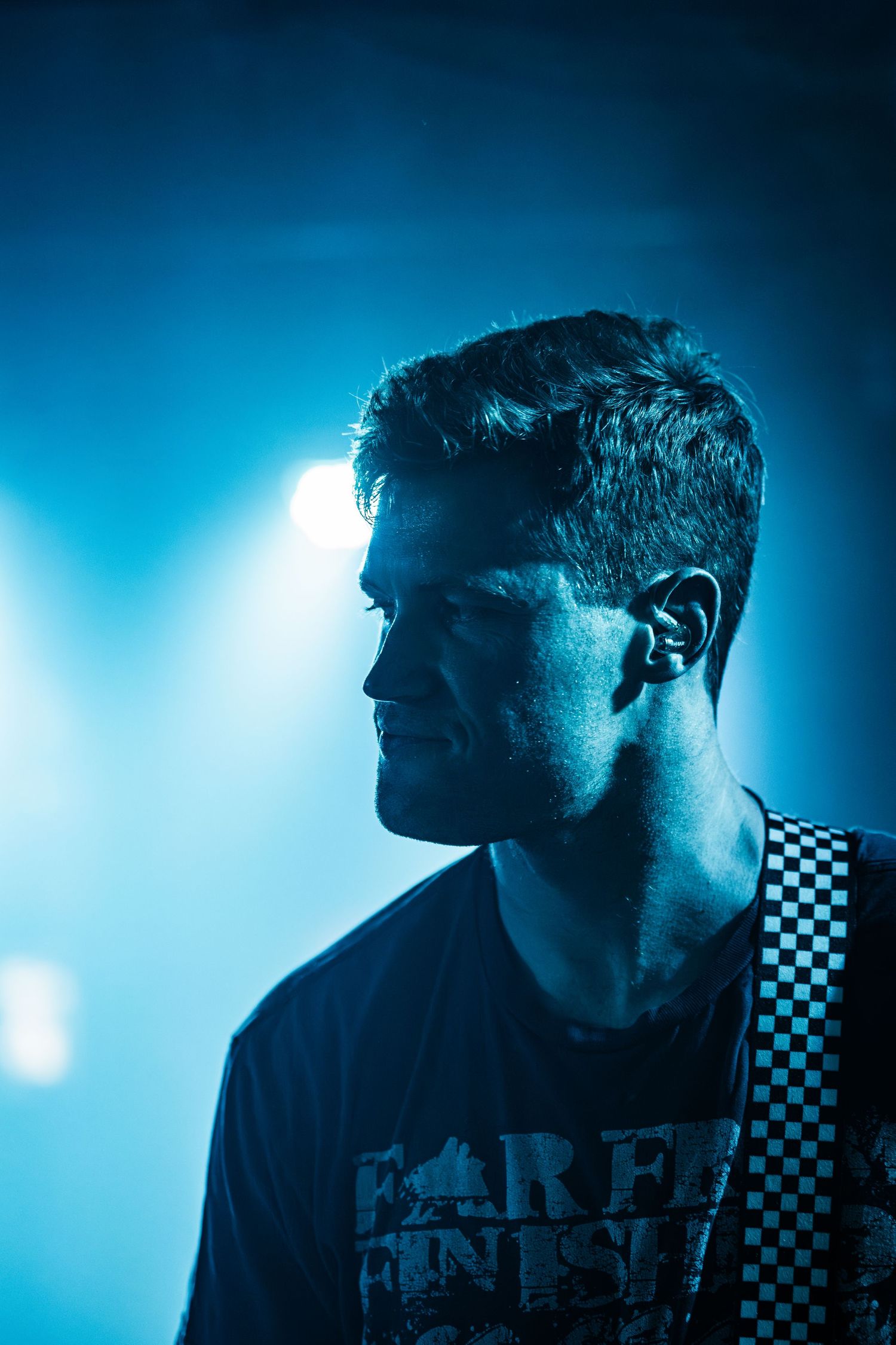 Dramatic side profile of performer silhouetted against blue stage lighting.