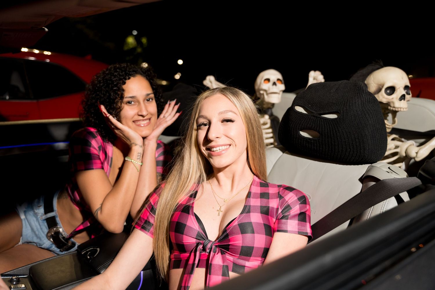 A car meet at night with Halloween decorations visible.