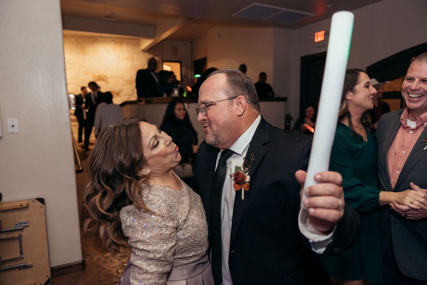 Couples dancing and celebrating at an indoor wedding reception with warm ambient lighting.