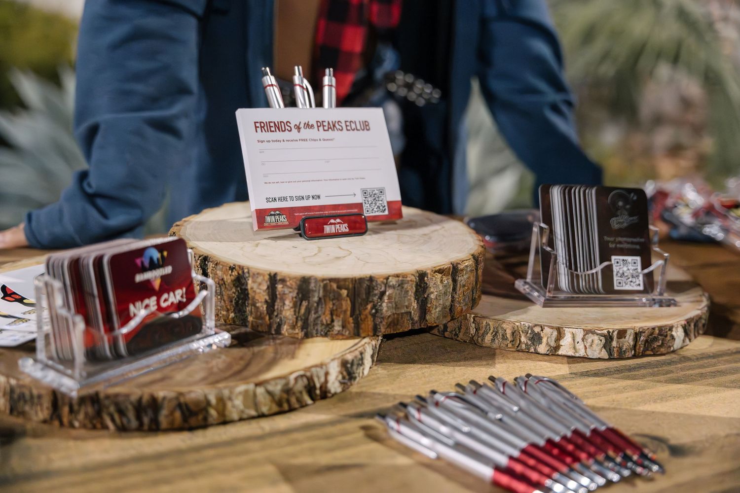 Close-up of promotional items displayed on rustic wood slices at event table.